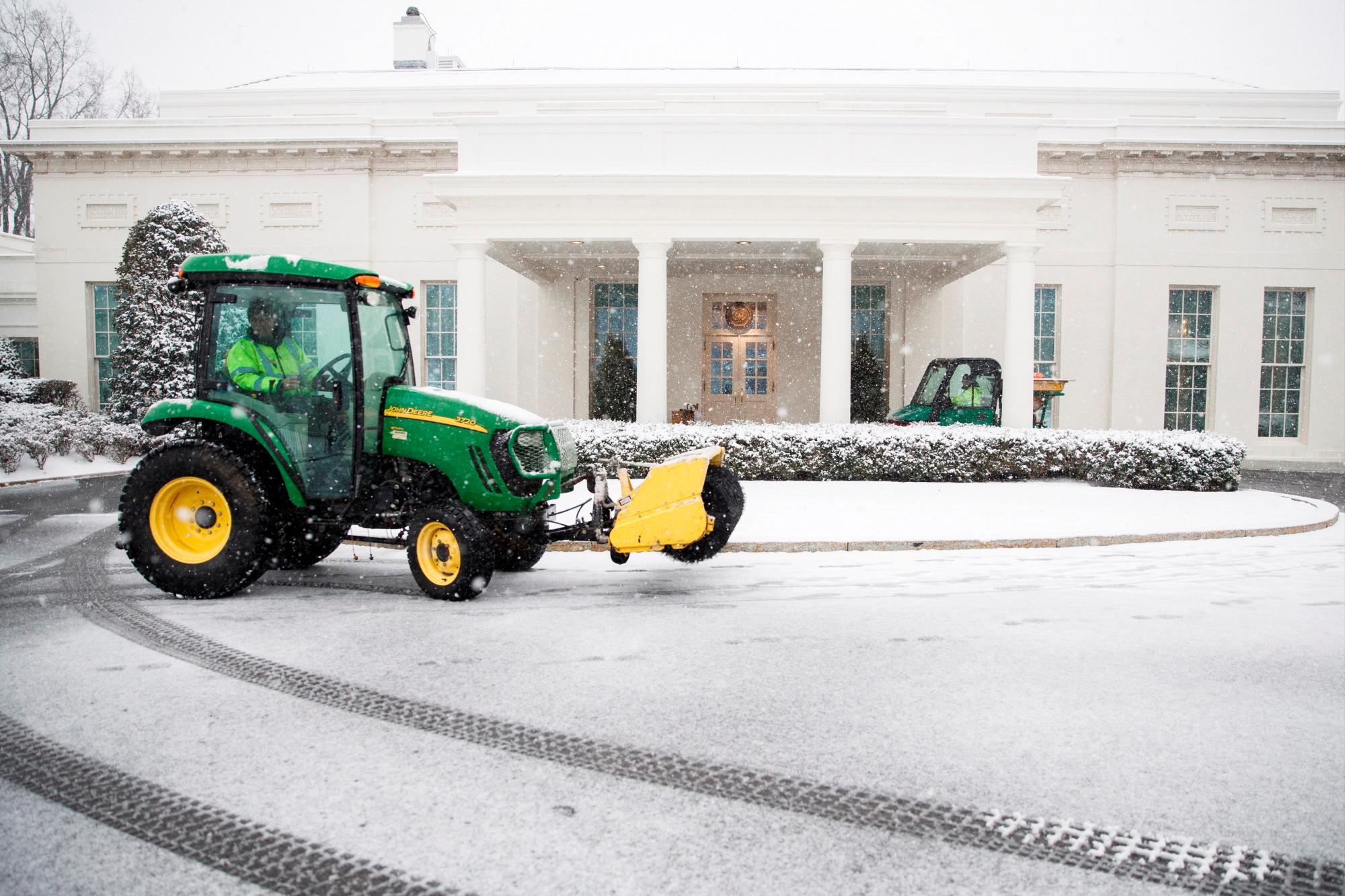 Varios operarios despejan de nieve un jardín en el exterior de la Casa Blanca en Washington D.C (Estados Unidos), durante una tormenta de nieve.