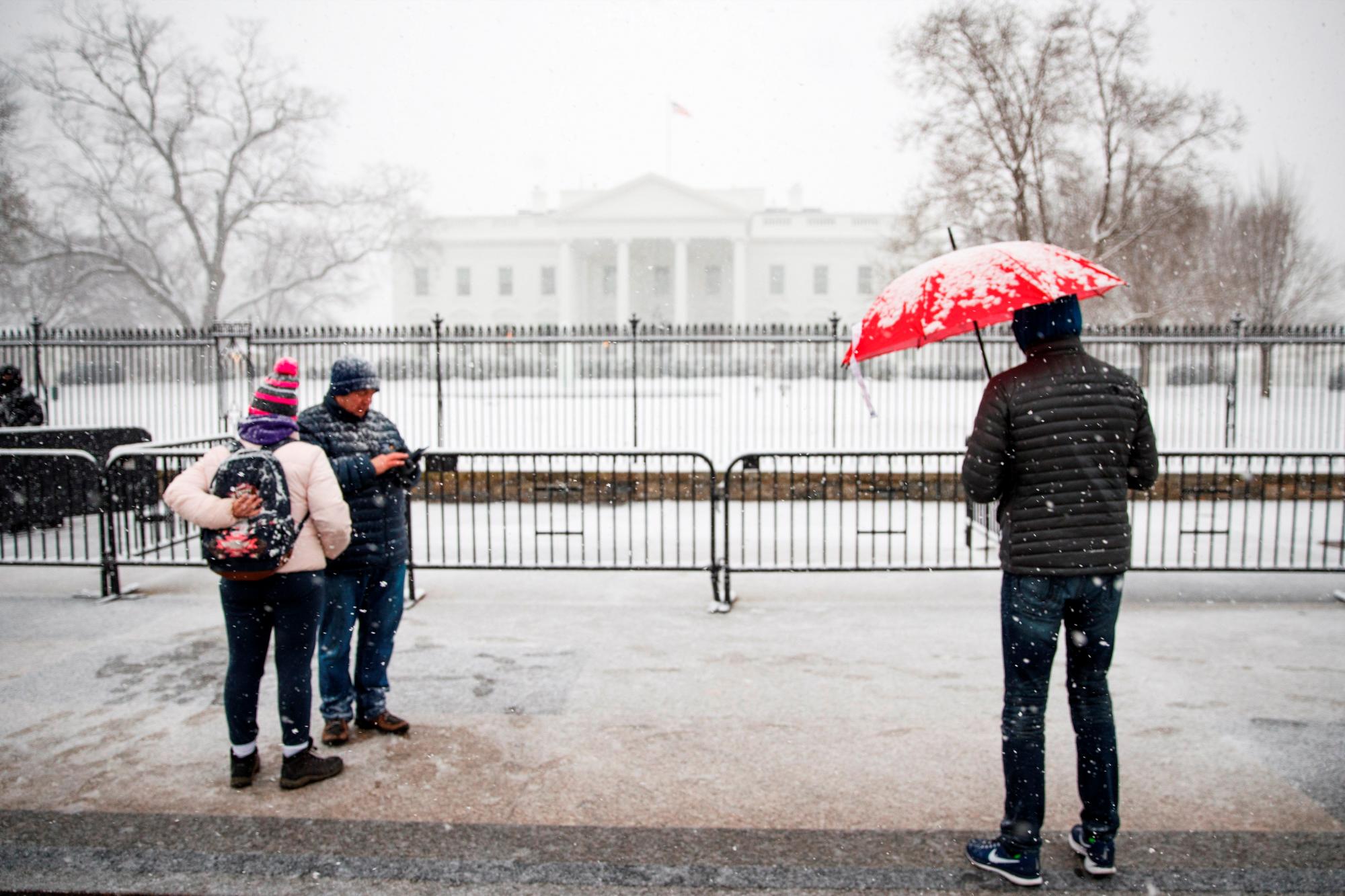 Varias personas contemplan el exterior nevado de la Casa Blanca en Washington D.C (Estados Unidos), durante una tormenta de nieve. 