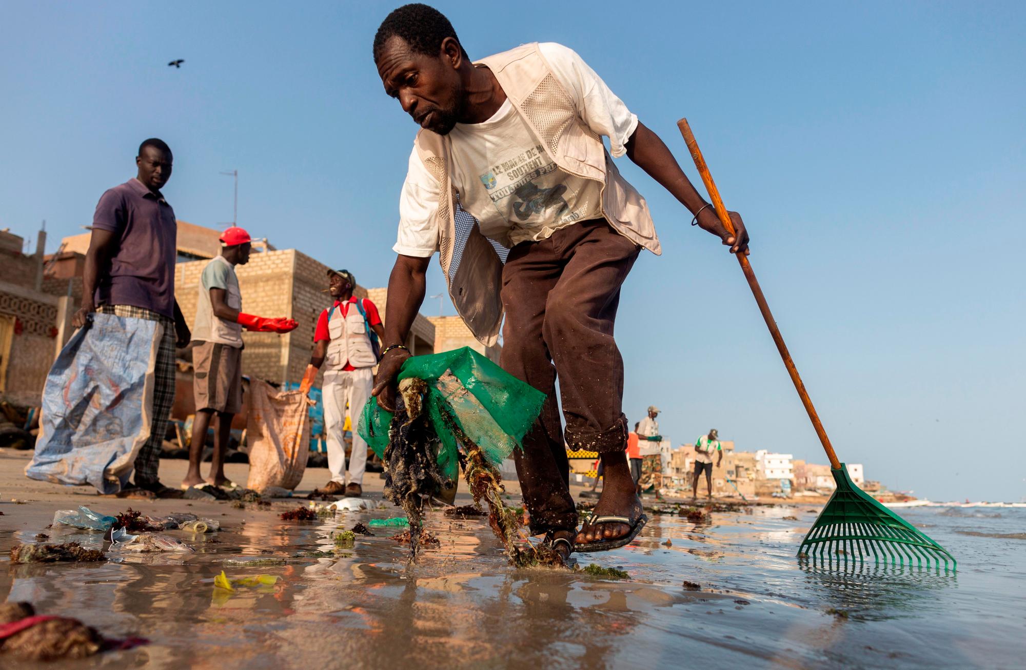 NGOR (SENEGAL), 12/03/2019.- Voluntarios senegaleses limpian la playa de la aldea de Ngor en Dakar, Senegal. El país africano desecha cada año decenas de miles de toneladas de plástico que acaba en el fondo del océano. Un problema que no solo afecta a su población costera, sino también a su economía. Debido a la falta de mecanismos de gestión de estos residuos por parte de los ayuntamientos, las comunidades han realizado sus propias limpiezas en algunas aldeas. Los ecologistas piden un cambio de política respecto al uso del plástico por parte del gobierno de Senegal. EFE/ Nic Bothma