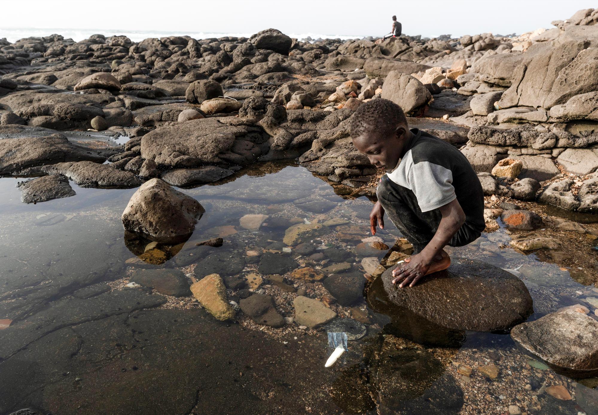 NGOR (SENEGAL), 12/03/2019.- Un niño senegalés juega con un barco hecho de plástico en la costa de la aldea de Ngor en Dakar, Senegal. El país africano desecha cada año decenas de miles de toneladas de plástico que acaba en el fondo del océano. Un problema que no solo afecta a su población costera, sino también a su economía. Debido a la falta de mecanismos de gestión de estos residuos por parte de los ayuntamientos, las comunidades han realizado sus propias limpiezas en algunas aldeas. Los ecologistas piden un cambio de política respecto al uso del plástico por parte del gobierno de Senegal. EFE/ Nic Bothma