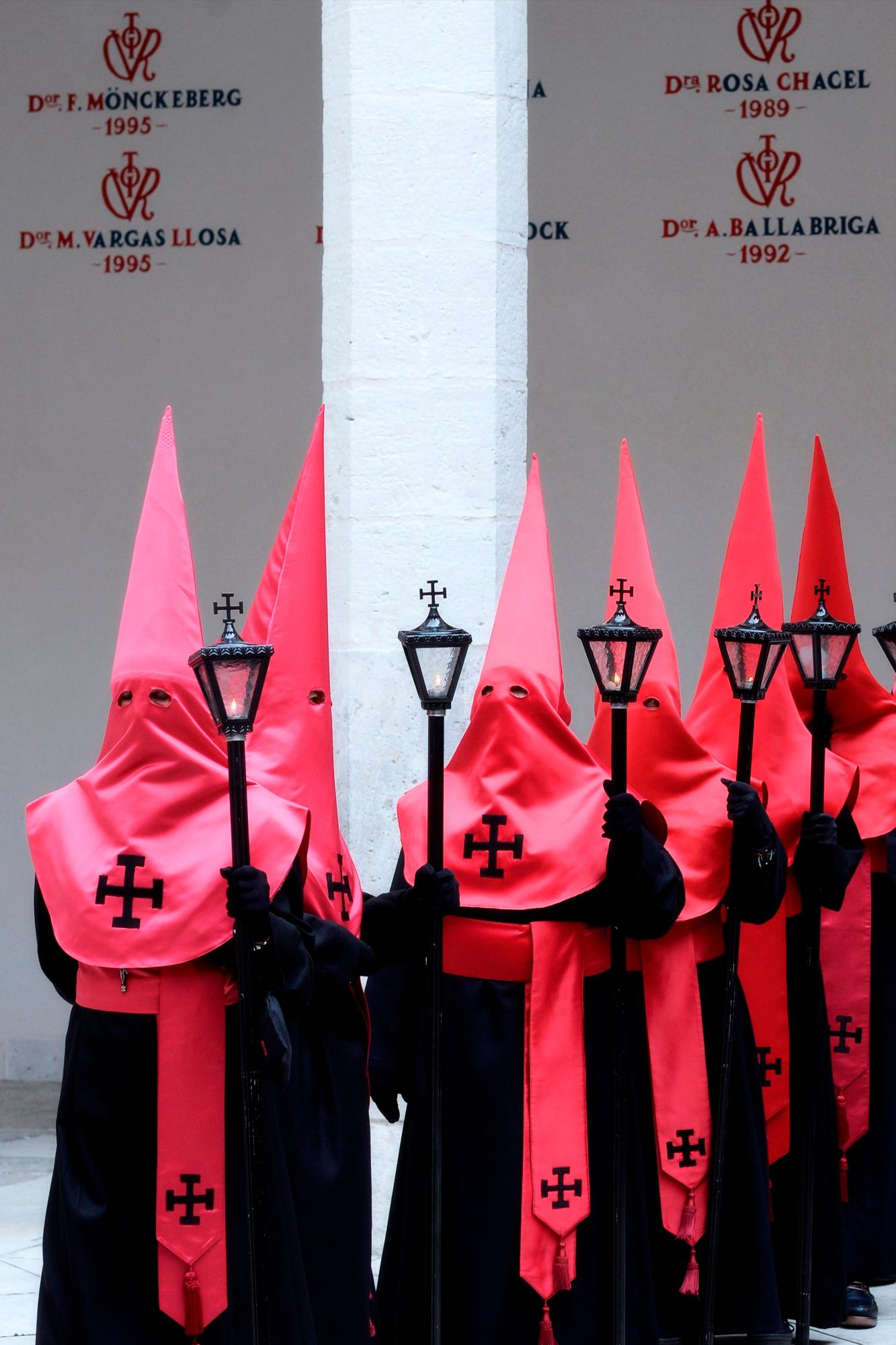 Cofrades de la Hermandad de El Cristo de la Luz, formada profesores y estudiantes de la Universidad de Valladolid, esperan la salida de la procesión de esta mañana de Jueves Santo, amenazada de suspensión por la lluvia. 