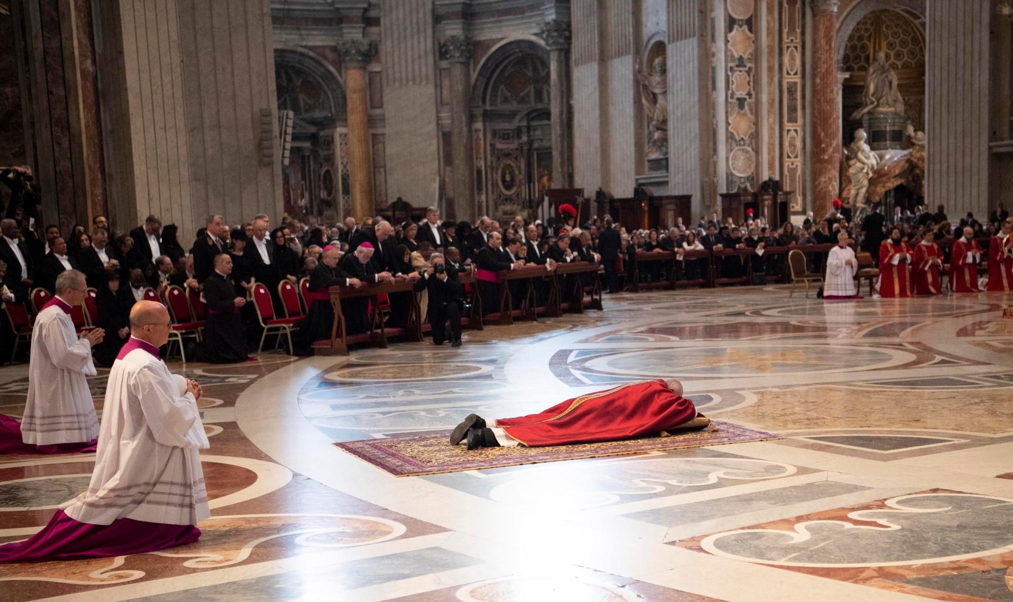 El papa Francisco (c) se tumba para rezar al presidir los ritos de Viernes Santo con la ceremonia de la Pasión del Señor en la basílica de San Pedro y el Vía Crucis en el Coliseo de Roma, centrado este año en la inmigración y la trata de personas. 