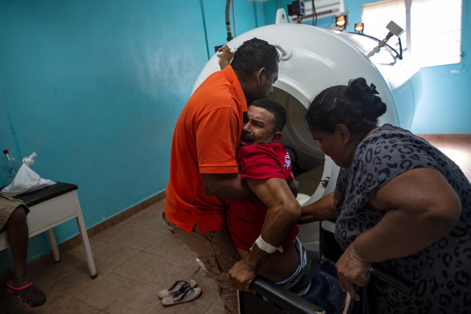 El fisioterapeuta Cedrak Waldan Mendoza, quien lleva el buzo de langosta Misael Banegas Díaz, de 49 años y paralizado por la enfermedad de descompresión, ingresa en una cámara hiperbárica en el hospital de Puerto Lempira, Honduras. 