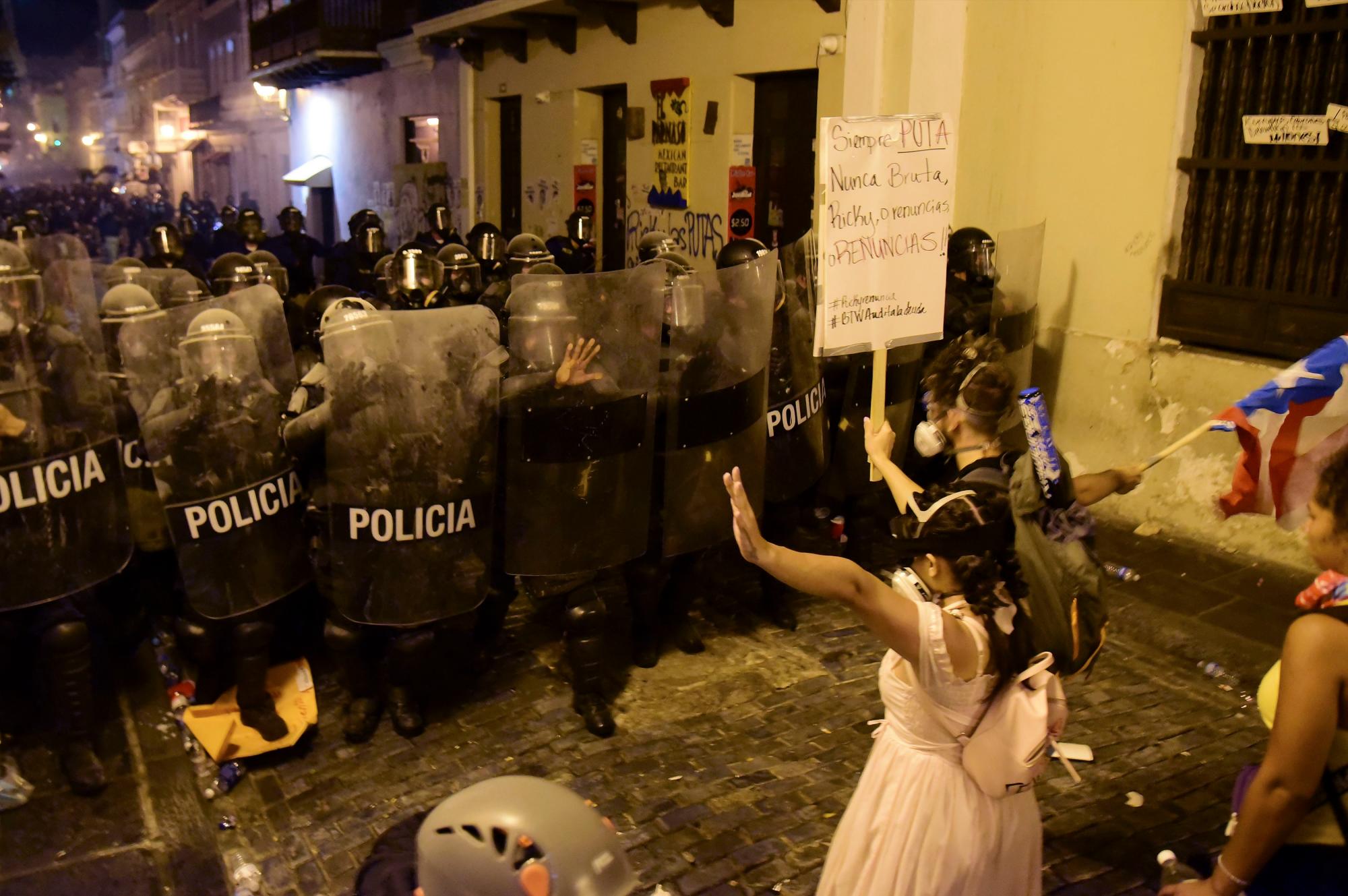 Los manifestantes reaccionan frente a la policía durante los enfrentamientos en San Juan, Puerto Rico, el miércoles 17 de julio de 2019.