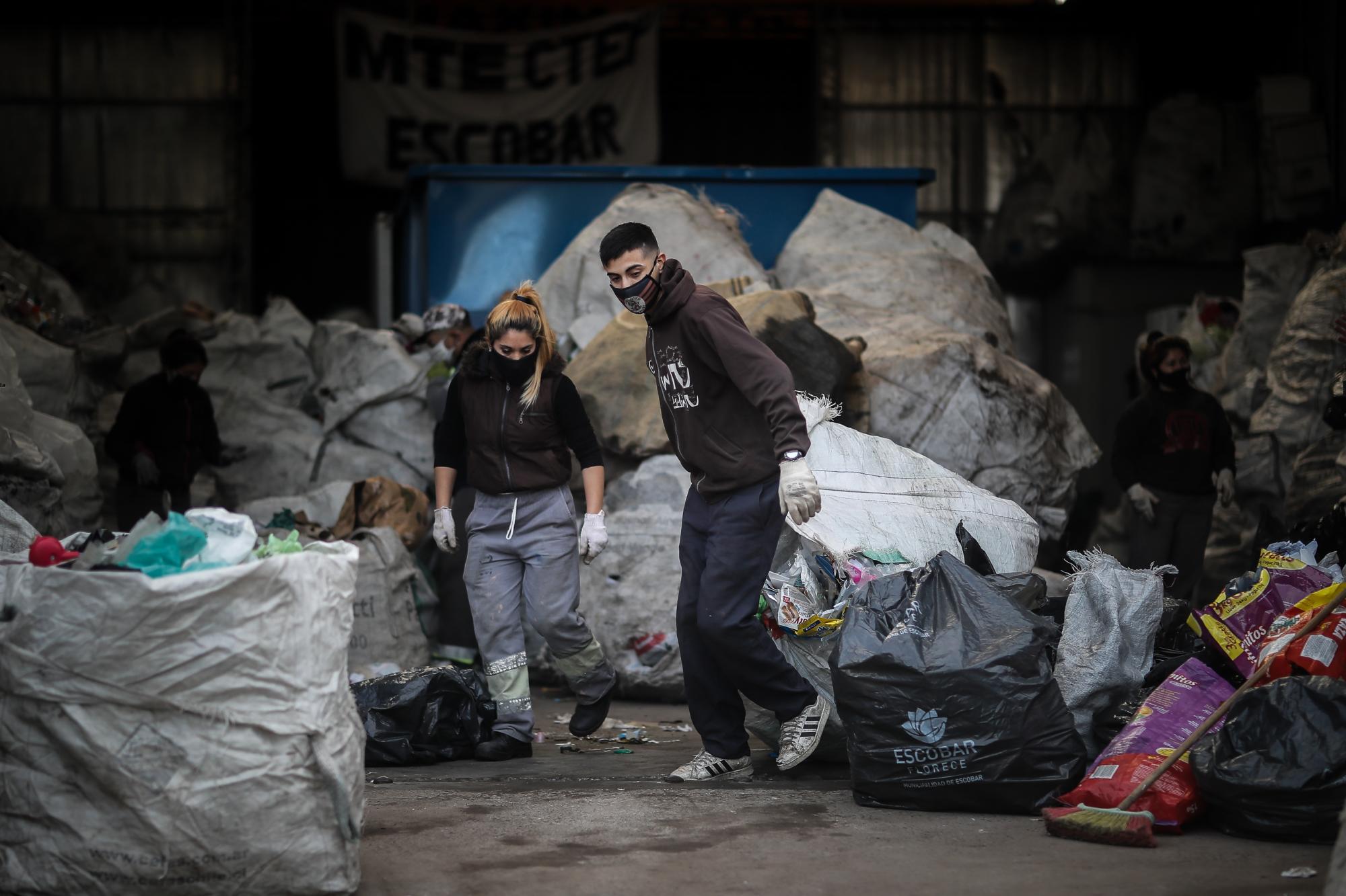 Dos recicladores, mejor conocidos como cartoneros cumplen su faena en el centro de la cooperativa 18 de Abril, en Escobar, Buenos Aires. (EFE/ Juan Ignacio Roncoroni)