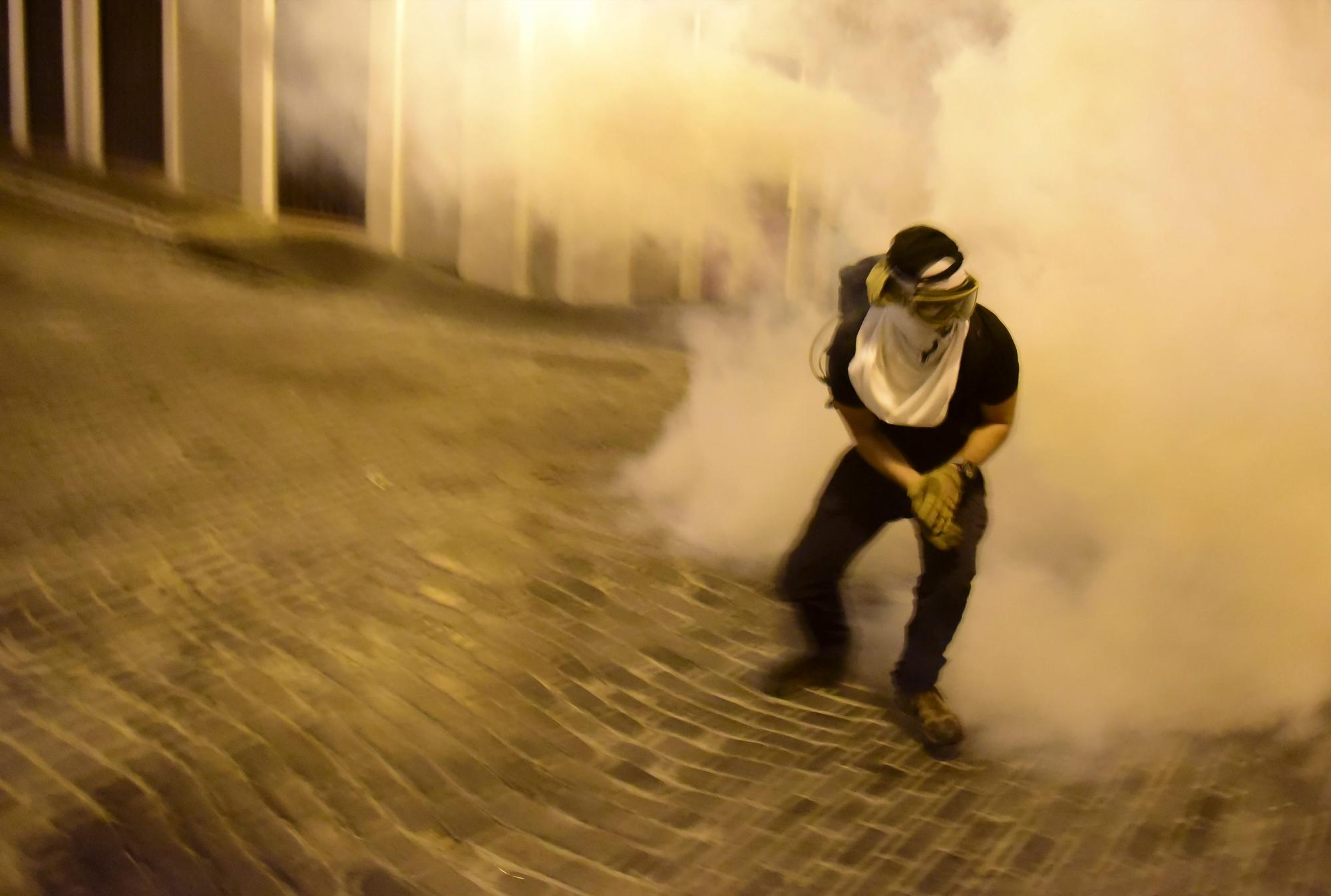 Un manifestante afectado por el gas lacrimógeno arrojado por la policía corre durante los enfrentamientos en San Juan, Puerto Rico, el miércoles 17 de julio de 2019. 