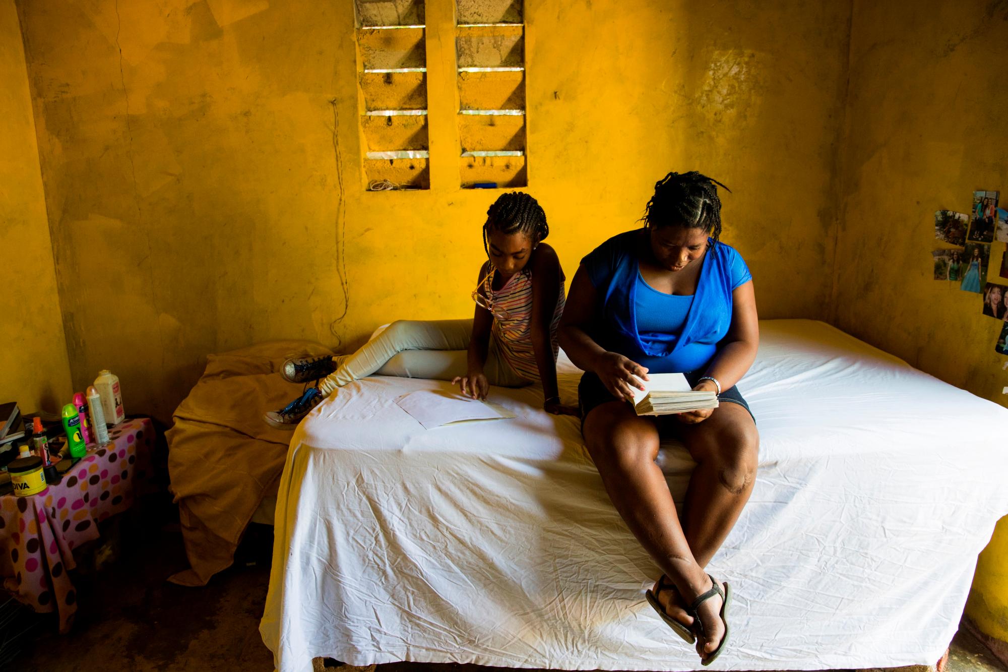 Fotografía del 8 de enero del 2020 que muestra a Marie Ange Haitis y a su hija Samantha, de 11 años, mientras observa un álbum de fotografías en su casa en Léogane (Haití). Los escándalos sexuales que rodean a la Minustah no son ningún secreto. 