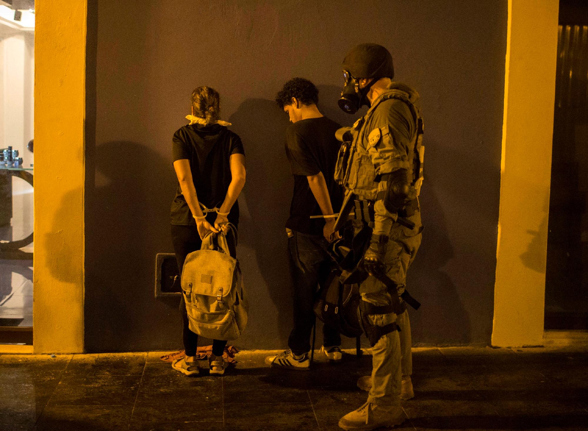 Un policía arresta a dos manifestantes durante los enfrentamientos en San Juan, Puerto Rico, el miércoles 17 de julio de 2019.