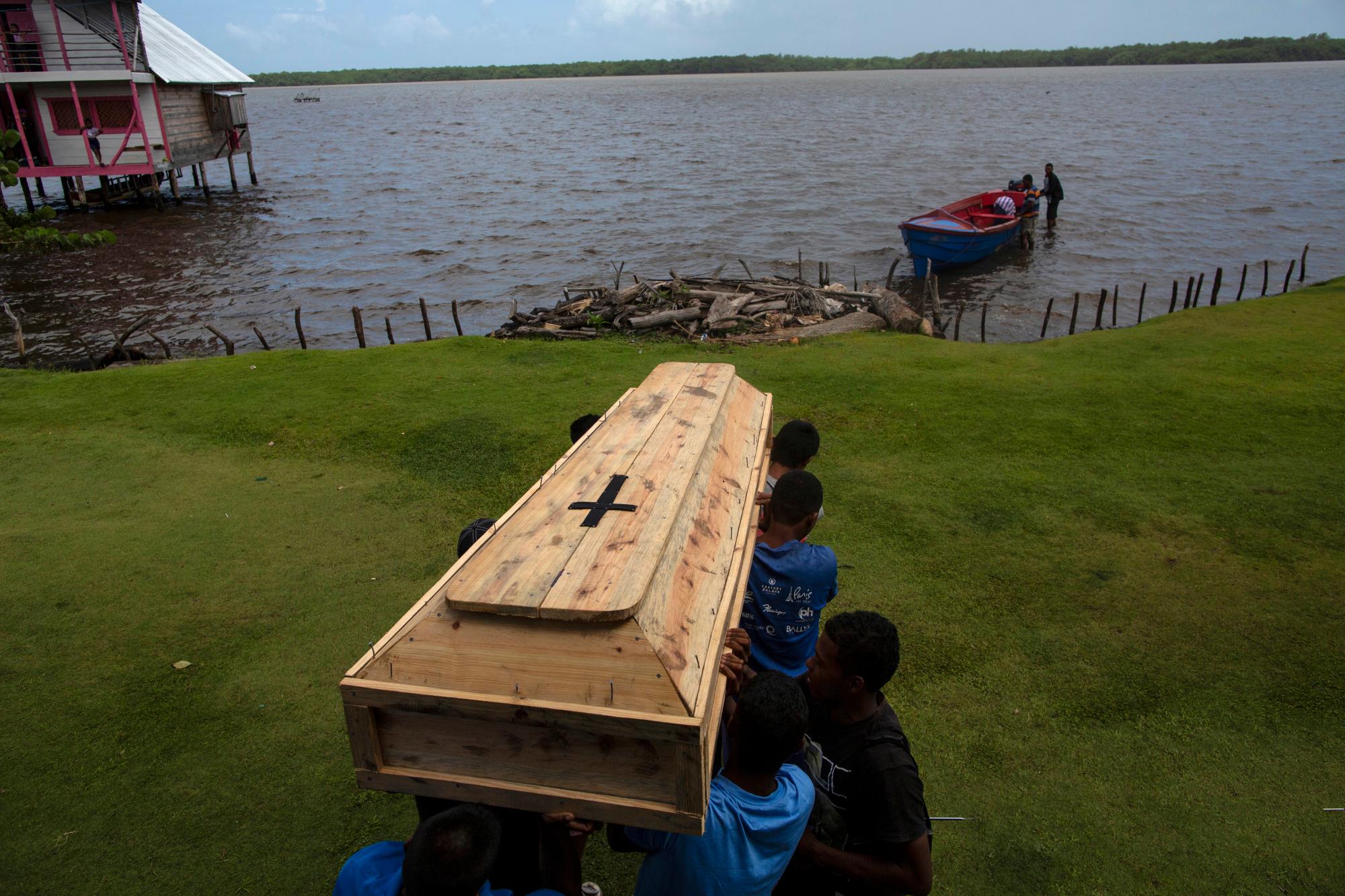Familiares y amigos llevan el ataúd que contiene los restos del buzo Miskito Oscar Salomon Charly, de 31 años, para ser transportados en un bote a un cementerio cercano, en Cabo Gracias a Dios, Nicaragua. Charly murió en Honduras luego de sufrir un grave caso de enfermedad por descompresión.