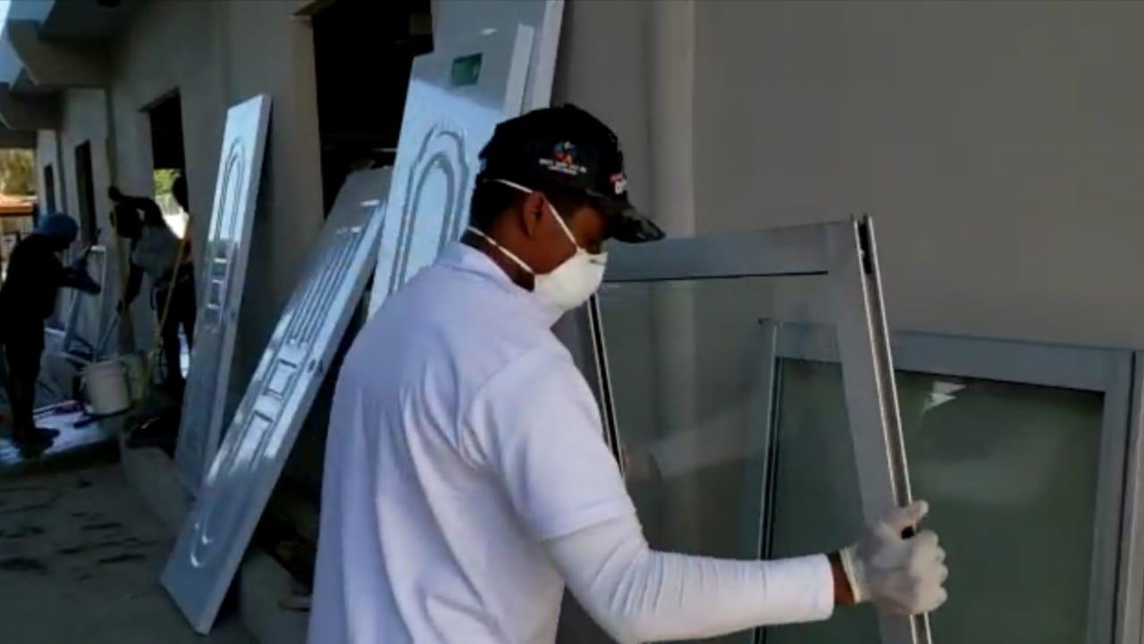 Personal encargado de instalar puertas y ventanas al local que fungirá como centro de aislamiento para pacientes con COVID-19. 