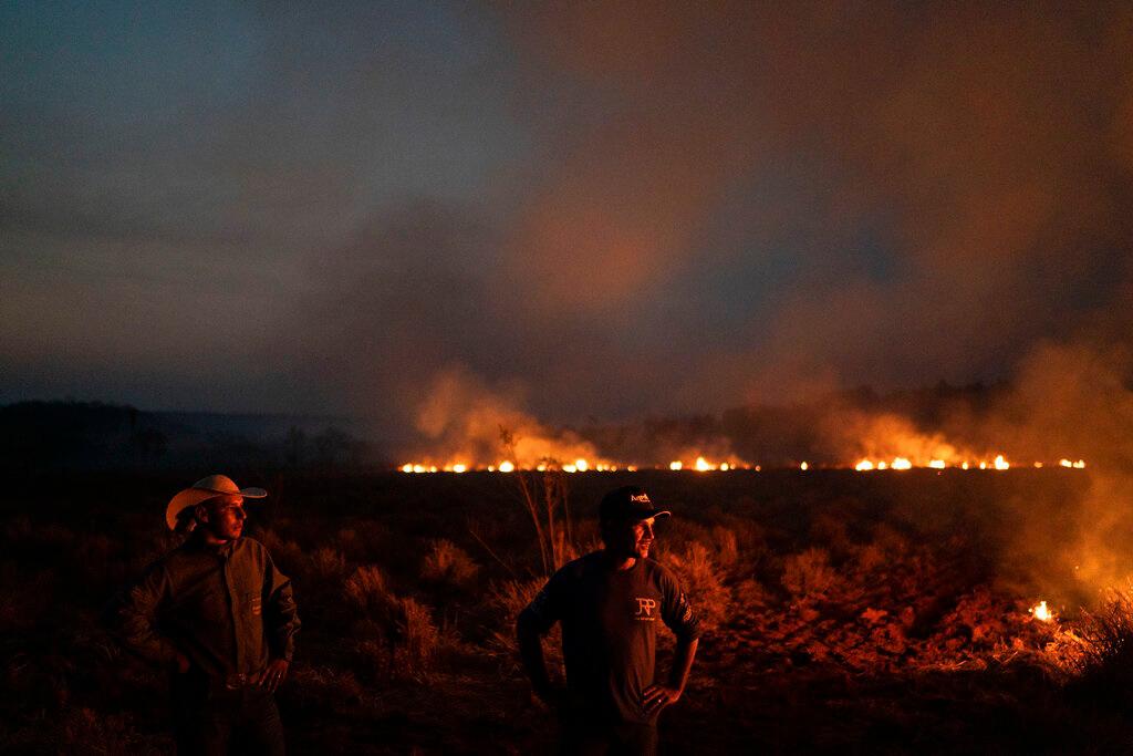 Neri dos Santos Silva, al centro, observa un incendio amenazante después de cavar trincheras para evitar que las llamas se propaguen a la granja en la que trabaja, en el municipio de Nova Santa Helena, en el estado de Mato Grosso, Brasil, el viernes 23 de agosto de 2019.
