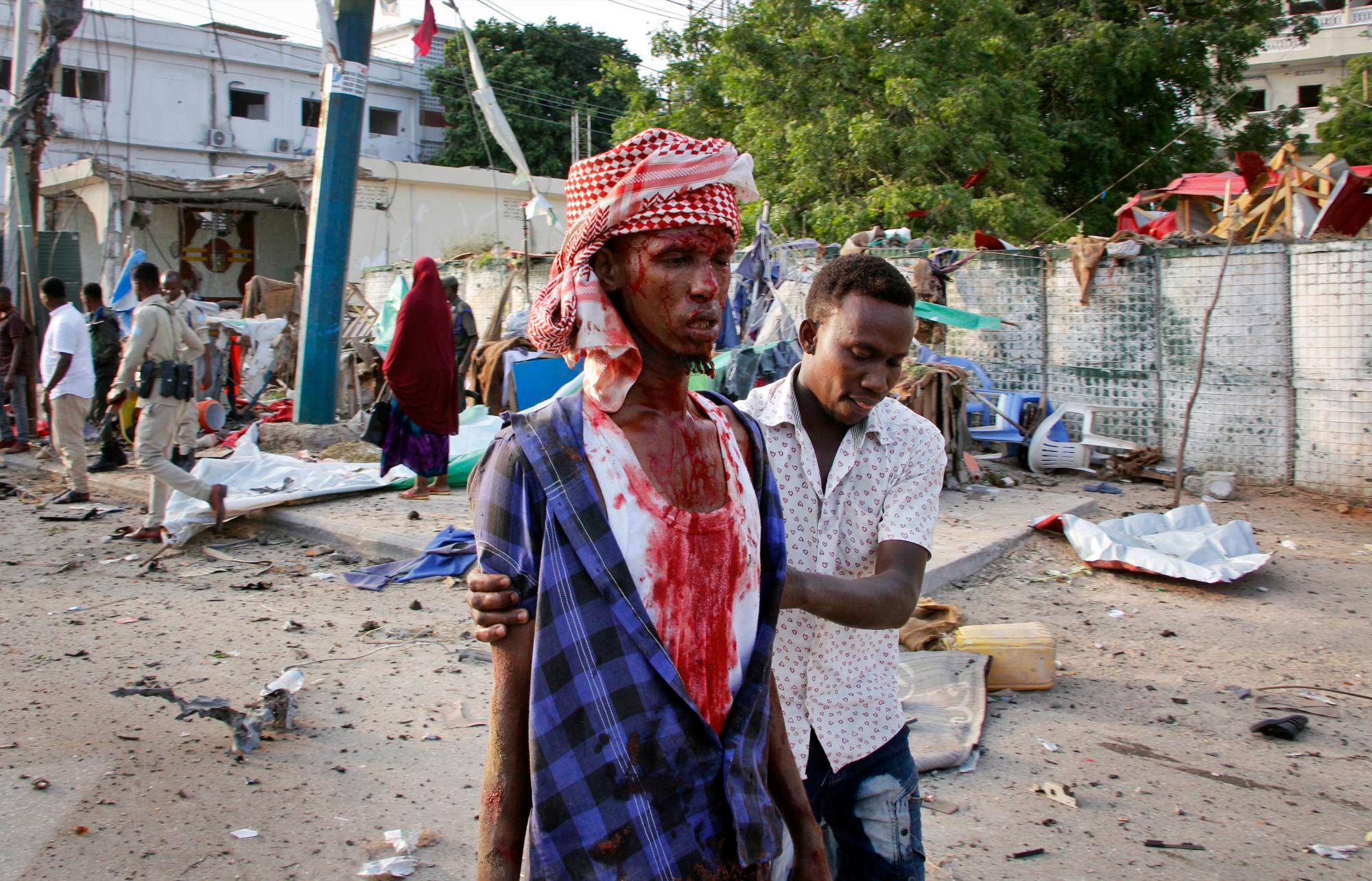 Un somalí ayuda a un civil herido que resultó herido en la explosión de una bomba cerca del hotel Sahafi.