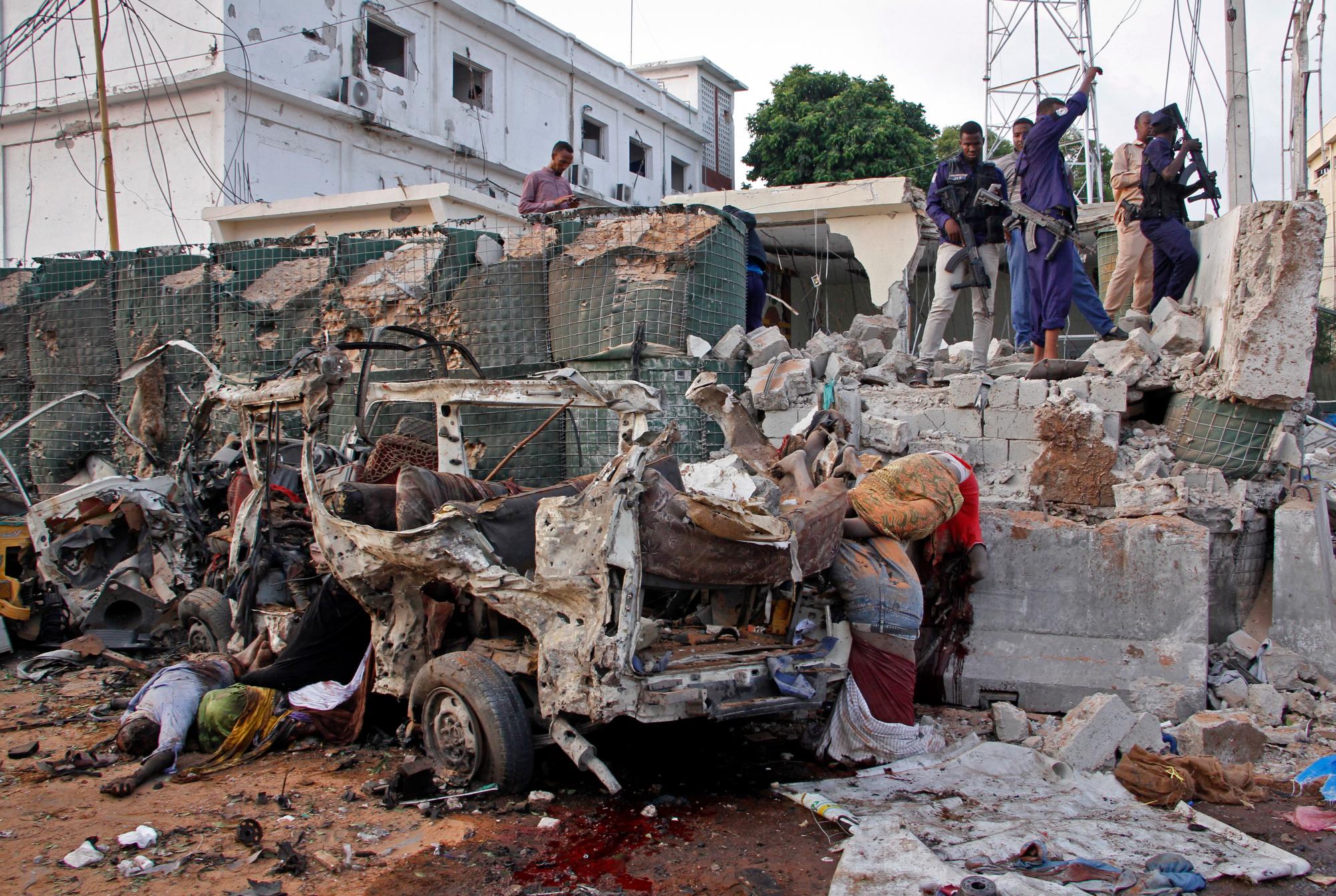 Security forces stand near bodies and the wreckage of vehicles at the scene of a bomb blast near the Sahafi hotel in the capital Mogadishu, Somalia Friday, Nov. 9, 2018. Four car bombs by Islamic extremists exploded outside the hotel, which is located across the street from the police Criminal Investigations Department, killing at least 20 people according to police. (AP Photo/Farah Abdi Warsameh)