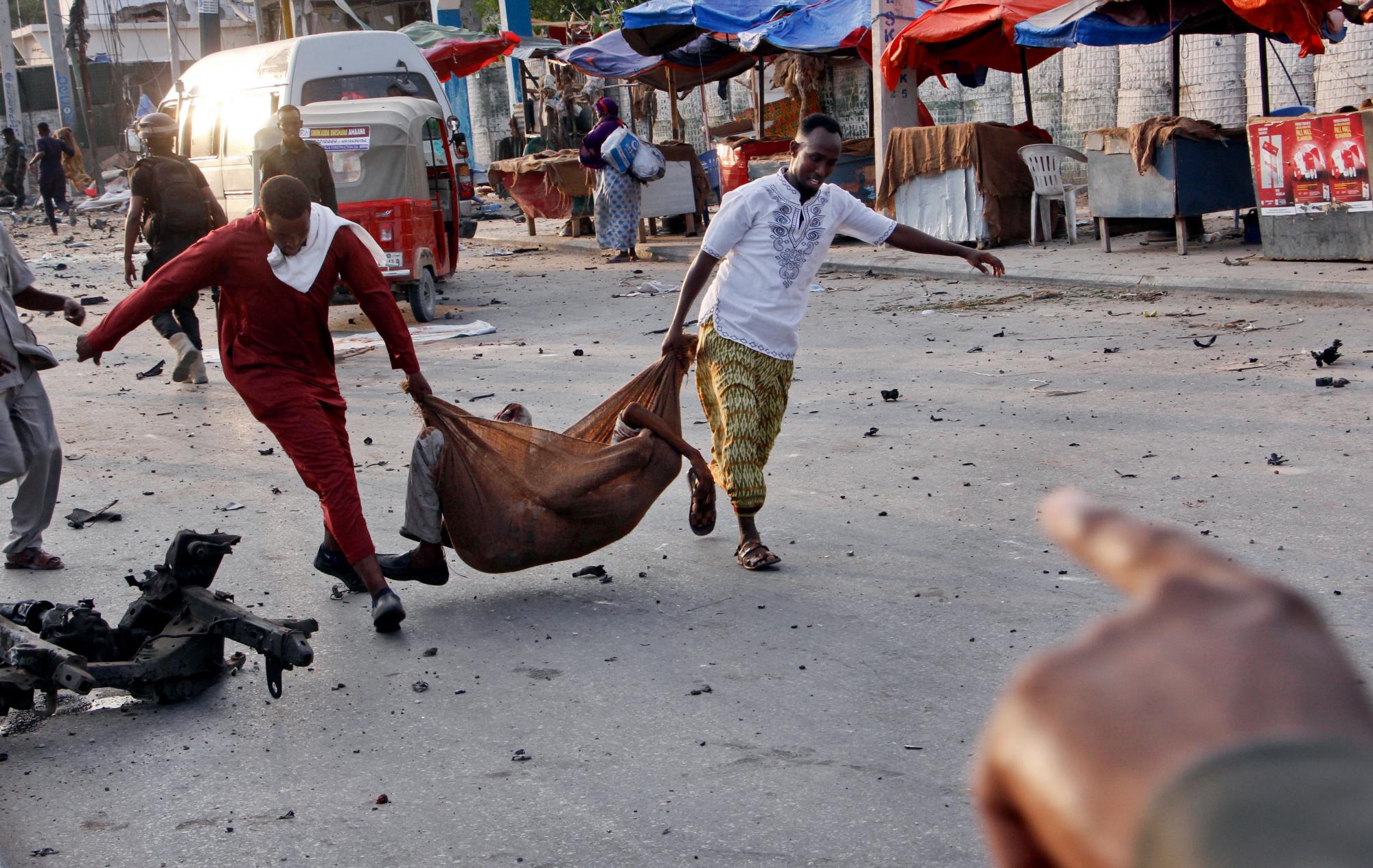 Somalíes se llevan a un civil herido en el lugar de la explosión de una bomba cerca del hotel Sahafi.