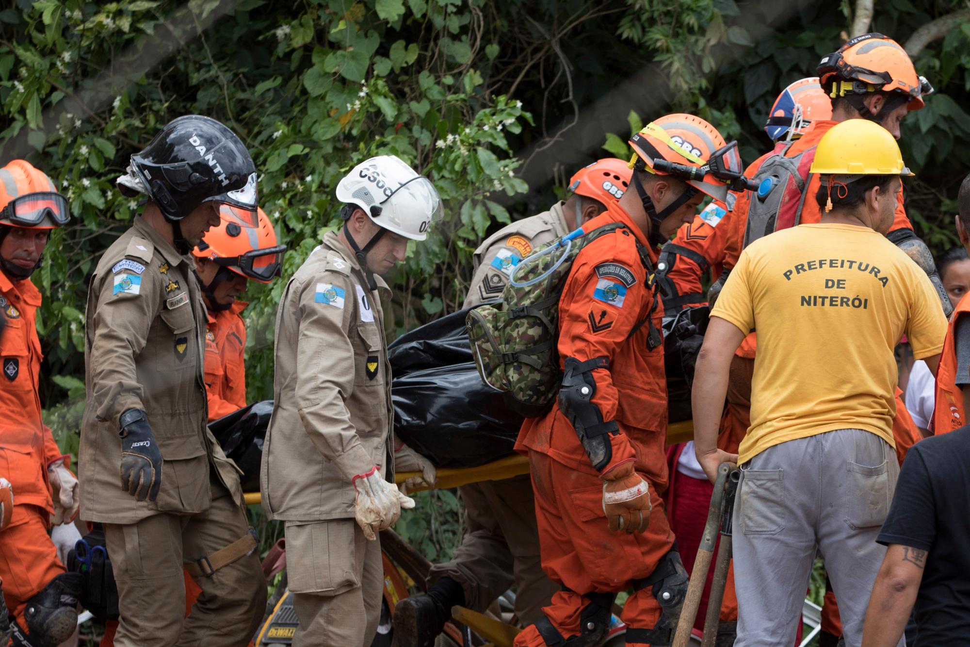 Los bomberos portan un cuerpo que fue encontrado debajo de los escombros después de un alud de lodo en Boa Esperanca o en la barriada “Good Hope” en Niteroi, Brasil, el sábado 10 de noviembre de 2018.