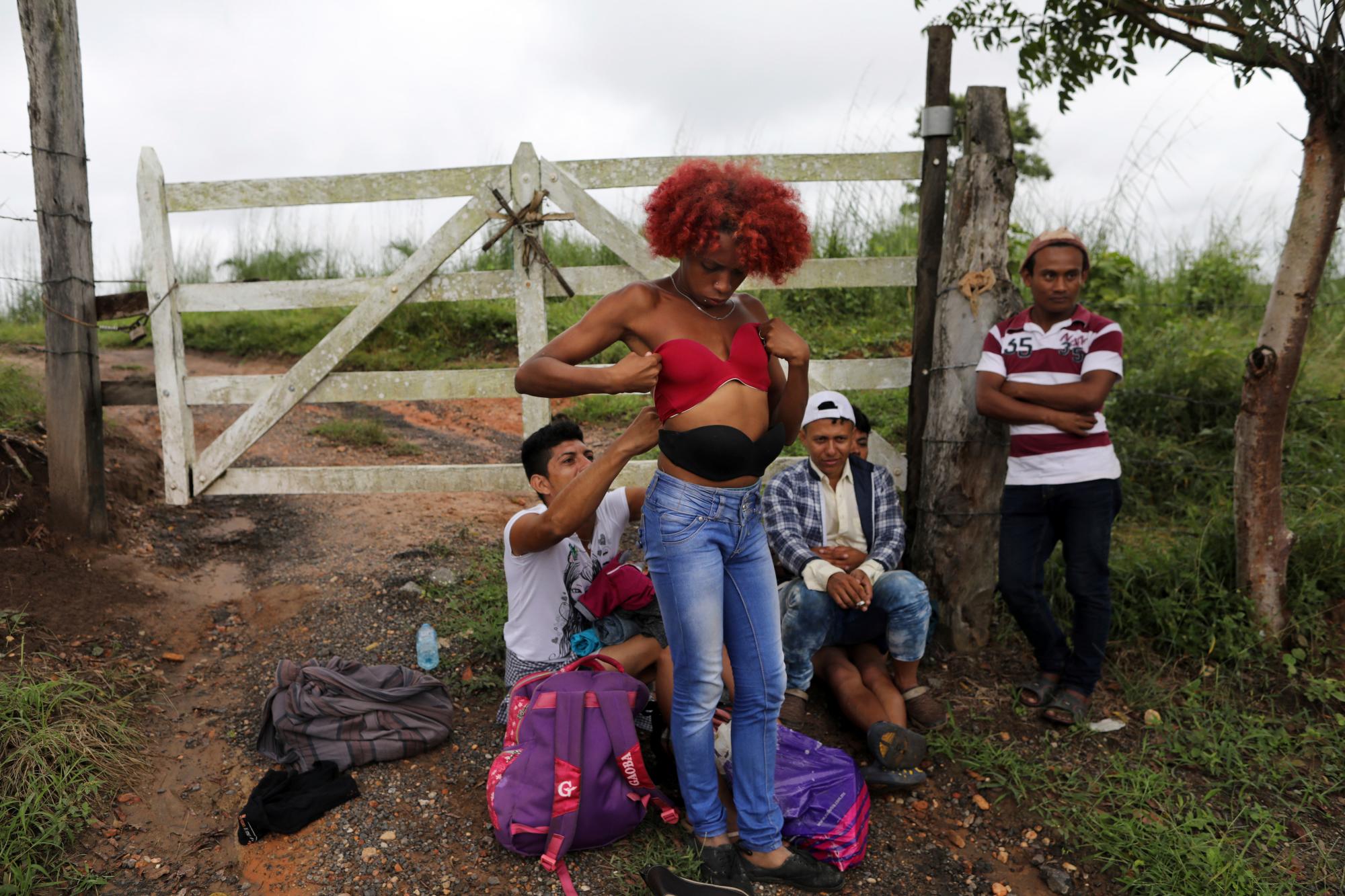La transgénero hondureña Alexa Amaya, que viaja con la caravana de migrantes con la esperanza de llegar a la frontera de los EE. UU., Se prueba un sostén que seleccionó de un montón de ropa donada que se encuentra en el camino a Sayula, México.