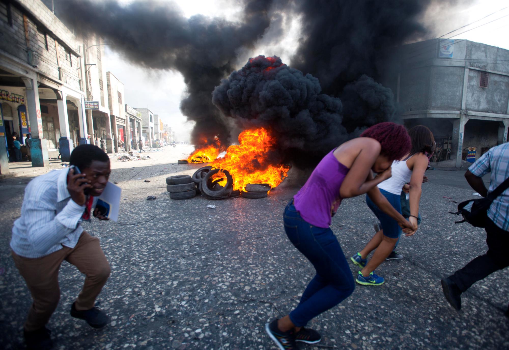 La gente pasa los neumáticos en llamas durante una protesta de la oposición que exige saber cómo los fondos de Petro Caribe han sido utilizados por las administraciones actuales y pasadas.