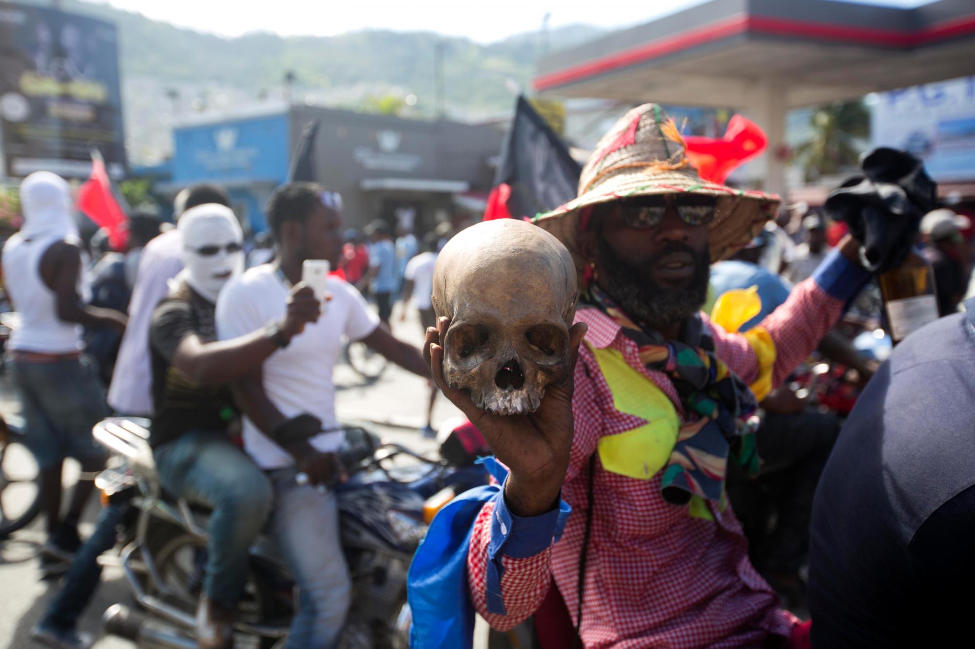 Un hombre sostiene una bandera de cráneo humano y vudú durante una protesta que exige saber cómo los fondos de Petro Caribe han sido utilizados por las administraciones actuales y pasadas.