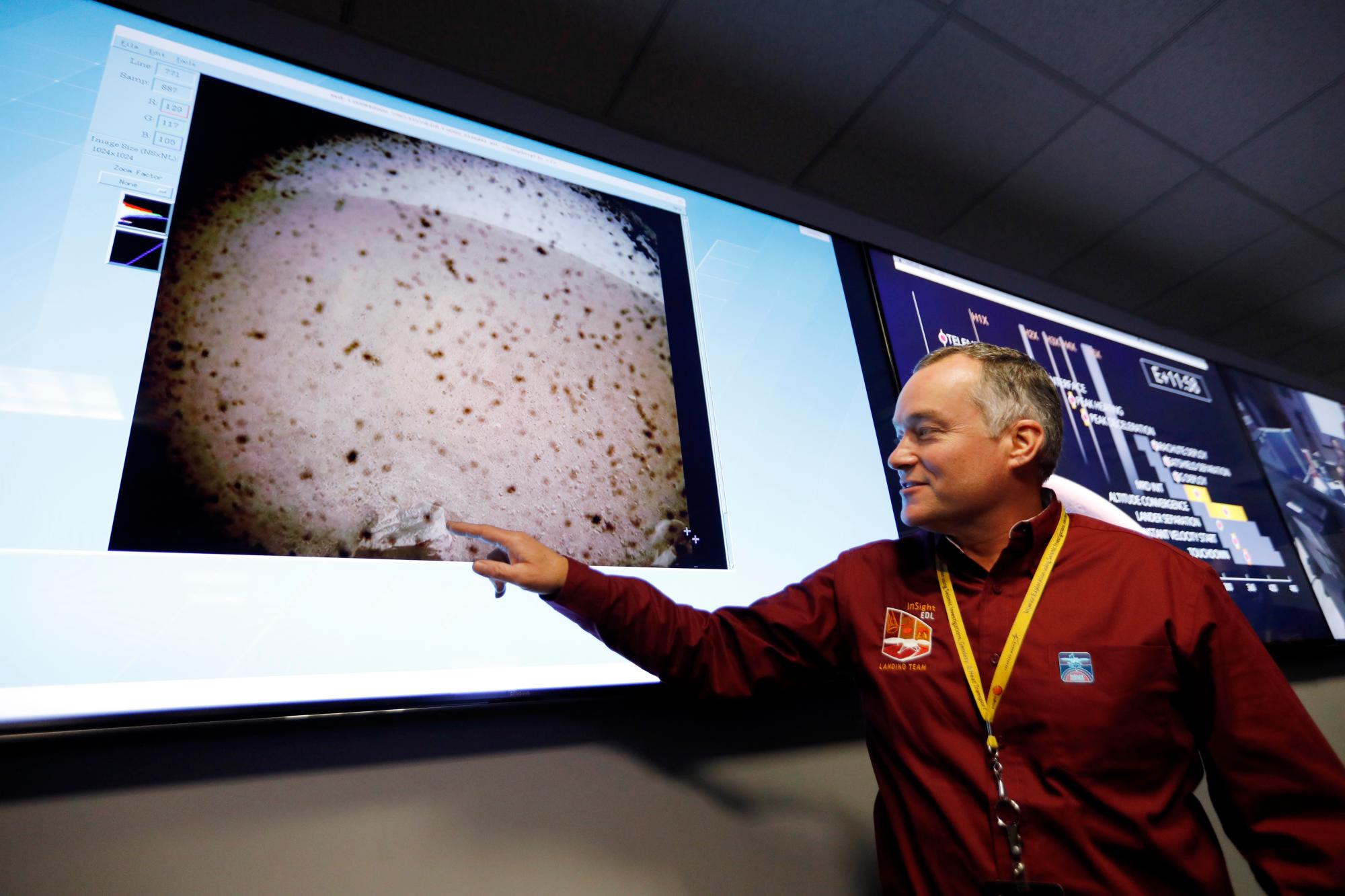 El gerente del proyecto de InSight, Tom Hoffman, señala una imagen enviada desde el aterrizaje de InSight luego de que la nave espacial aterrizó en Marte en el área de apoyo a la misión de la instalación de operaciones de vuelo espacial en el Laboratorio de Propulsión a Chorro de la NASA el lunes 26 de noviembre de 2018, en Pasadena, California. 