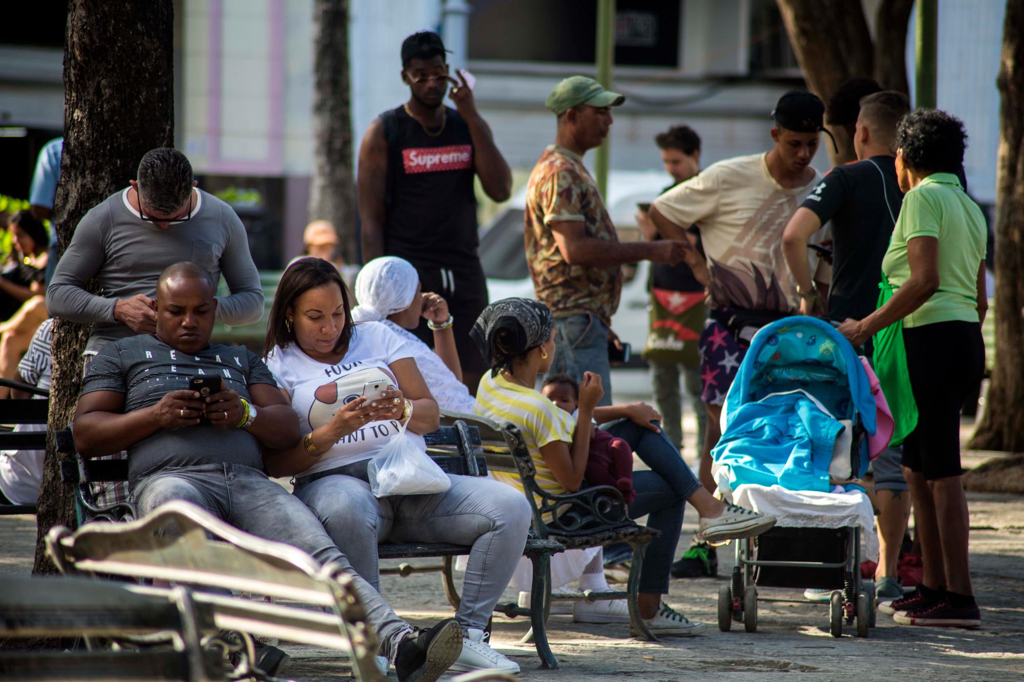 La gente navega por Internet en sus teléfonos inteligentes en un punto de conexión Wi-Fi patrocinado por el gobierno en un parque en La Habana, Cuba, el jueves 6 de diciembre de 2018. Por primera vez, los cubanos pueden inscribirse en el servicio de Internet 3G para su móvil teléfonos, con paquetes que van desde 600 megabytes por aproximadamente $ 7 hasta cuatro gigabytes por aproximadamente $ 30 meses.