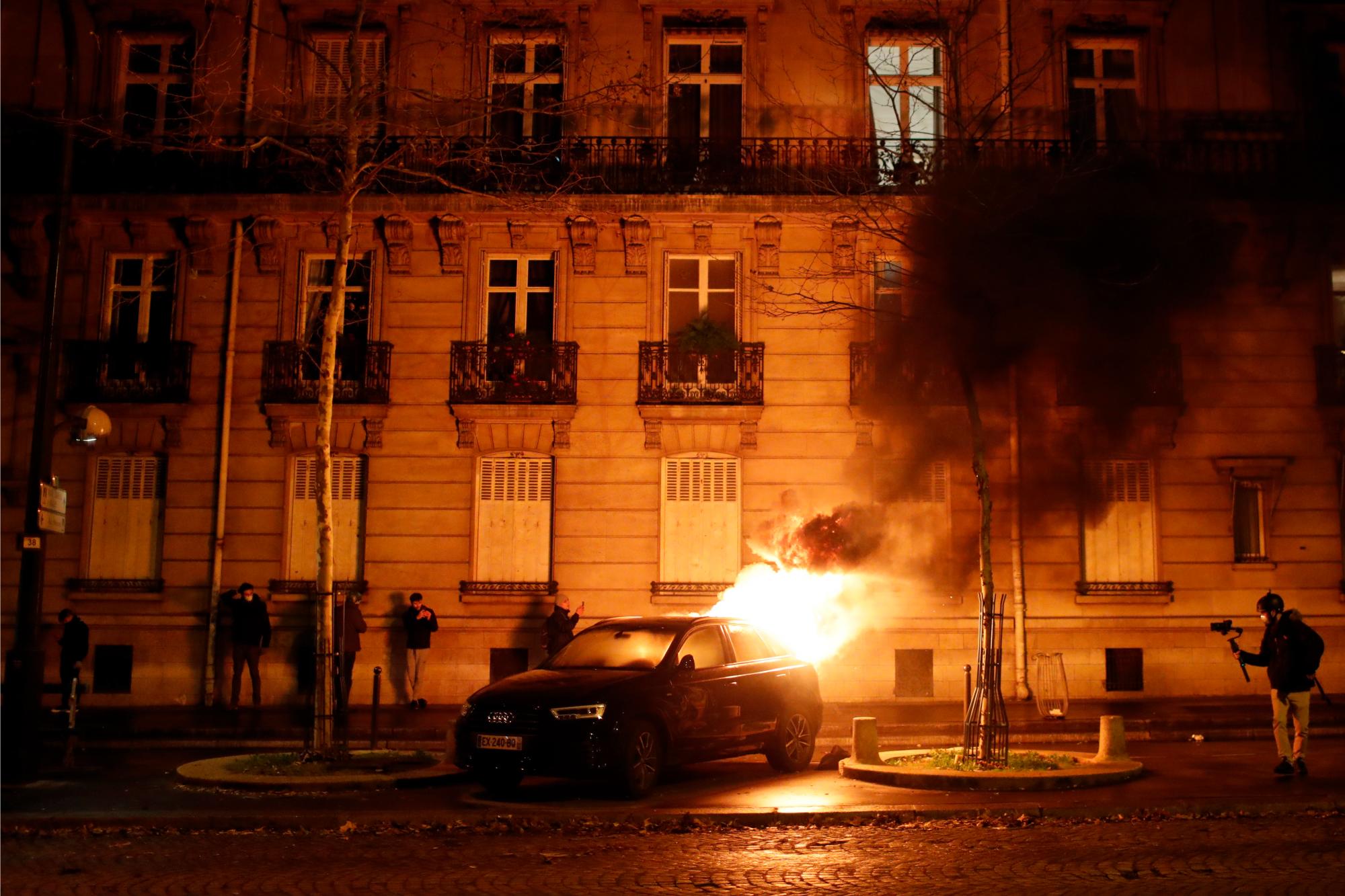 Un carro ardiente encendido por los manifestantes se observa frente a un edificio en París, Francia.