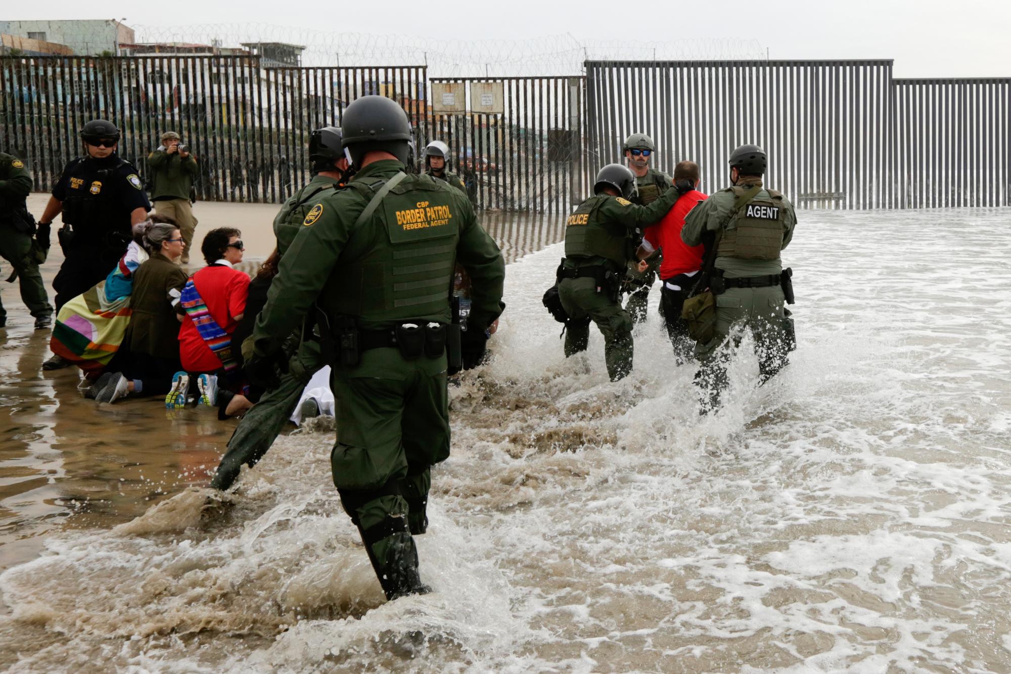 Agentes de la Patrulla Fronteriza, derecha, detienen a un hombre durante una protesta en la frontera con Tijuana, México, en San Diego. 