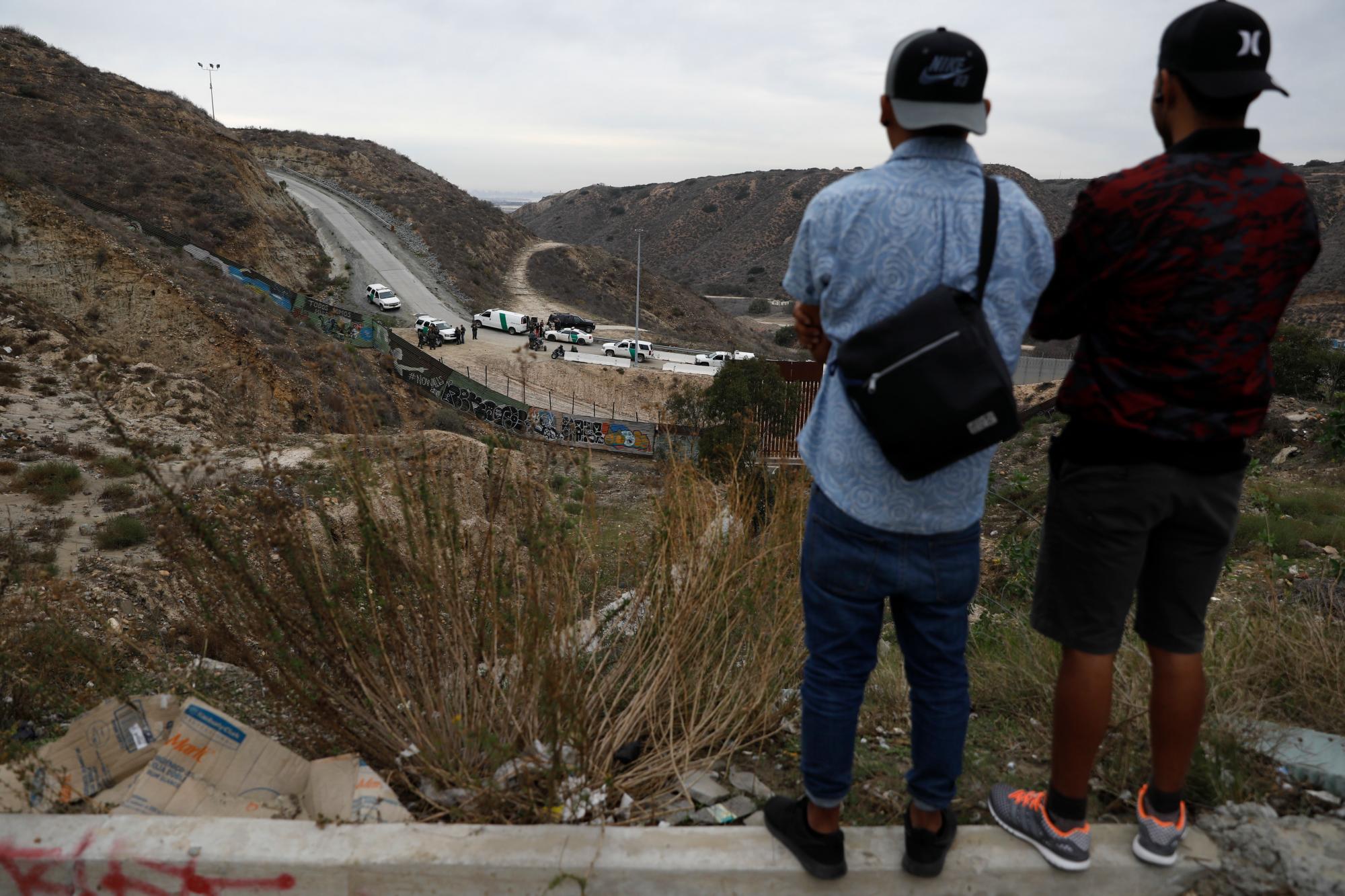Dos jóvenes hondureños observan desde el territorio mexicano mientras un grupo de solicitantes de asilo, incluidos sus primos, son detenidos desde Tijuana, México.