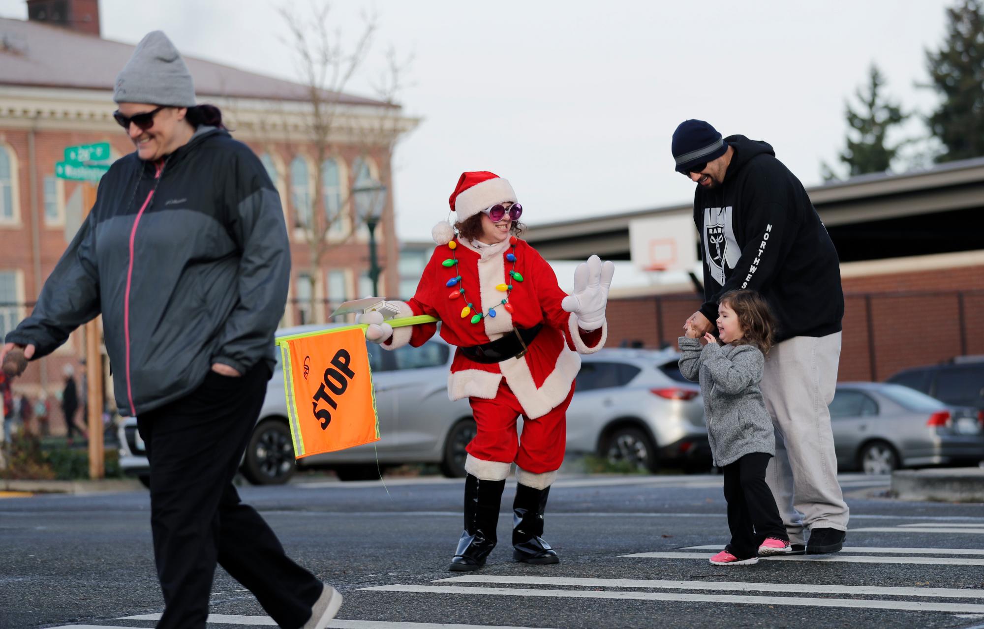 Peggy Cleary Tonnema viste un traje de Santa mientras trabaja como guardia de cruce, el viernes 21 de diciembre de 2018, frente a la Escuela Primaria Washington en Tacoma.