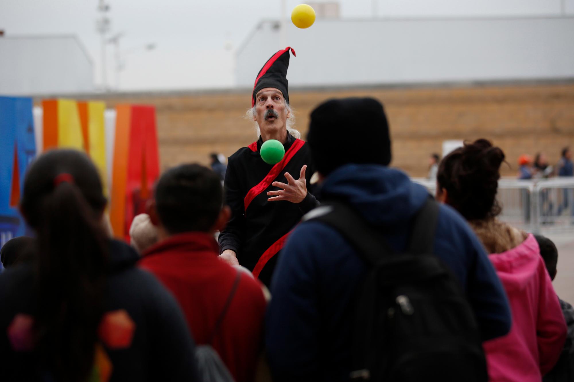 Un artista callejero actua para los migrantes quienes esperan una oportunidad de asilo en EE.UU.