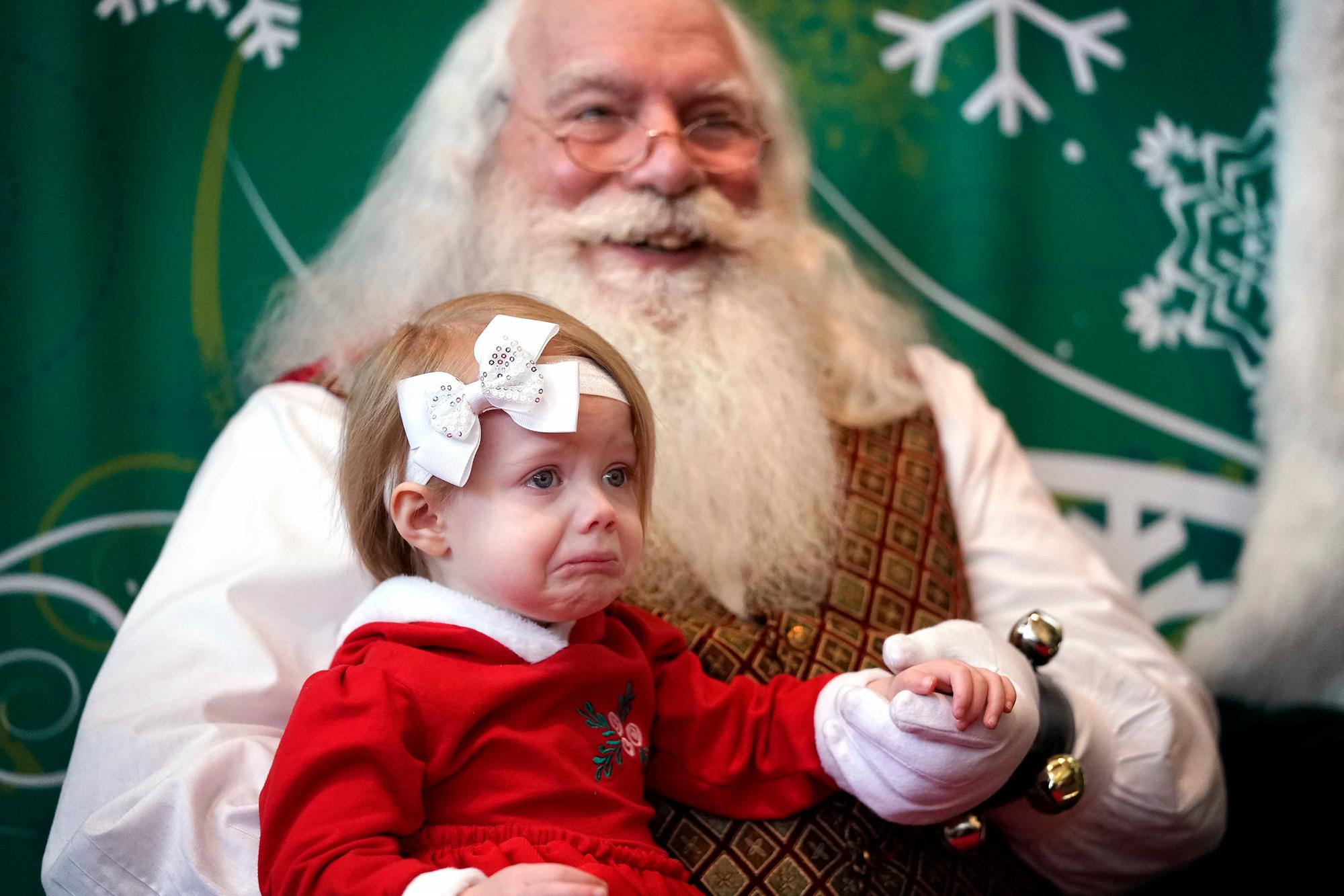 Aeris Smith, de 19 meses, de Hopkins retiene las lágrimas mientras posa para una foto con Santa en el Southdale Center en Edina, Minnesota.