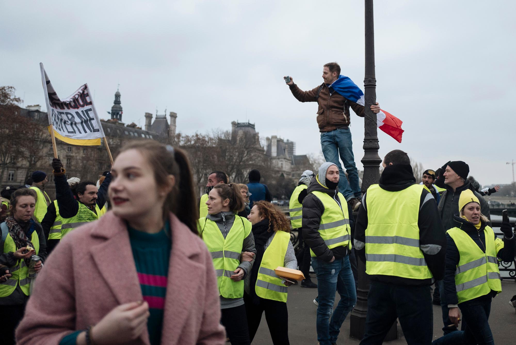 Un manifestante que lleva la bandera nacional francesa toma imágenes con sus teléfonos móviles durante una protesta por un chaleco amarillo en París, el sábado 5 de enero de 2019. Cientos de manifestantes intentaban dar nueva vida al movimiento francés del chaleco, aparentemente en decadencia, en Francia. y reuniones en otras ciudades.