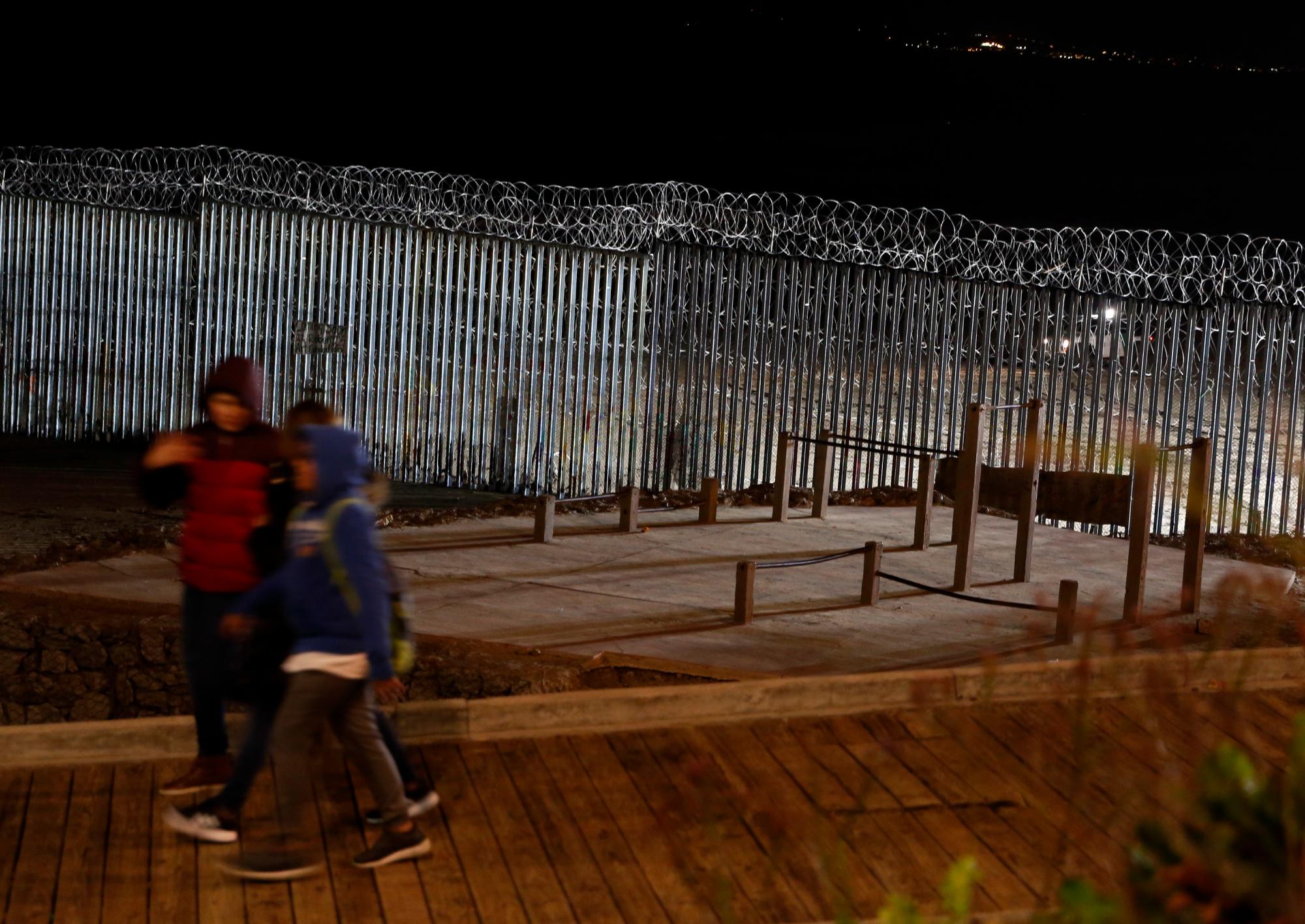 Proyectores de luz de los Estados Unidos, iluminan el muro fronterizo coronado con alambre de púas en la playa en Tijuana, México.