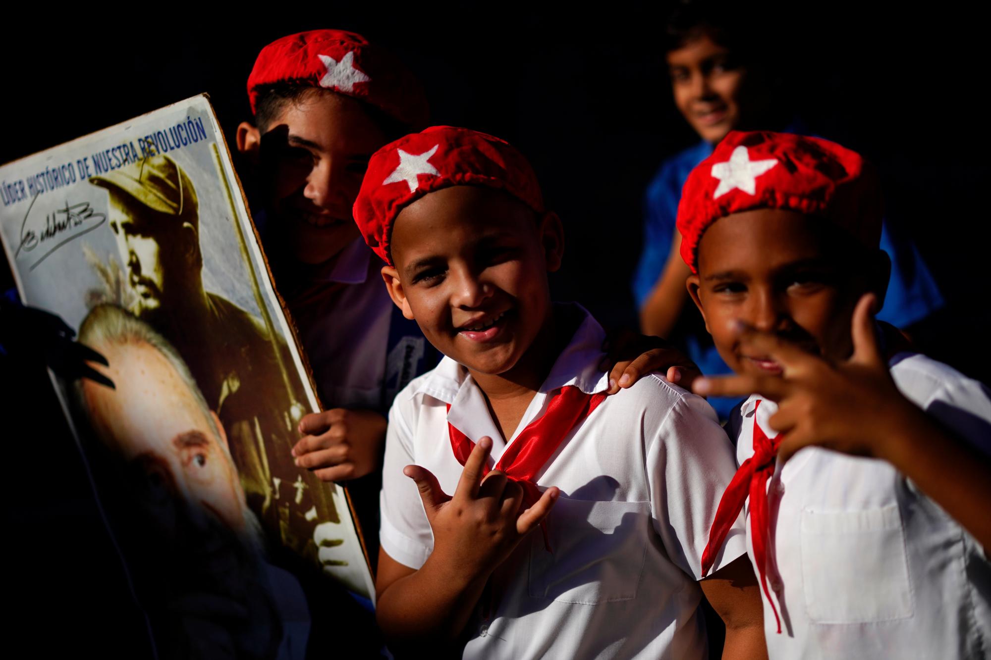 Los jóvenes asisten a una marcha que celebra el 60 aniversario de la llegada de Fidel Castro, en el cartel de la izquierda, y su ejército rebelde a Regla, un área dentro de La Habana, Cuba. Castro y sus rebeldes llegaron a La Habana en una caravana el 8 de enero de 1959, después de derrocar al dictador Fulgencio Batista.