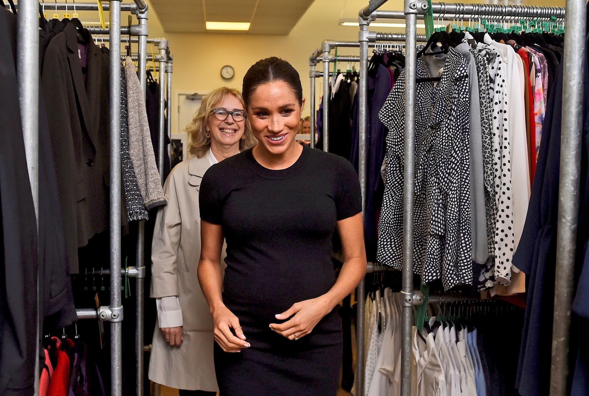 Meghan, la duquesa de Sussex, acompañada por Juliet Hughes-Hallett, pasa entre estantes de ropa en un centro de la organización benéfica Smart Works.
