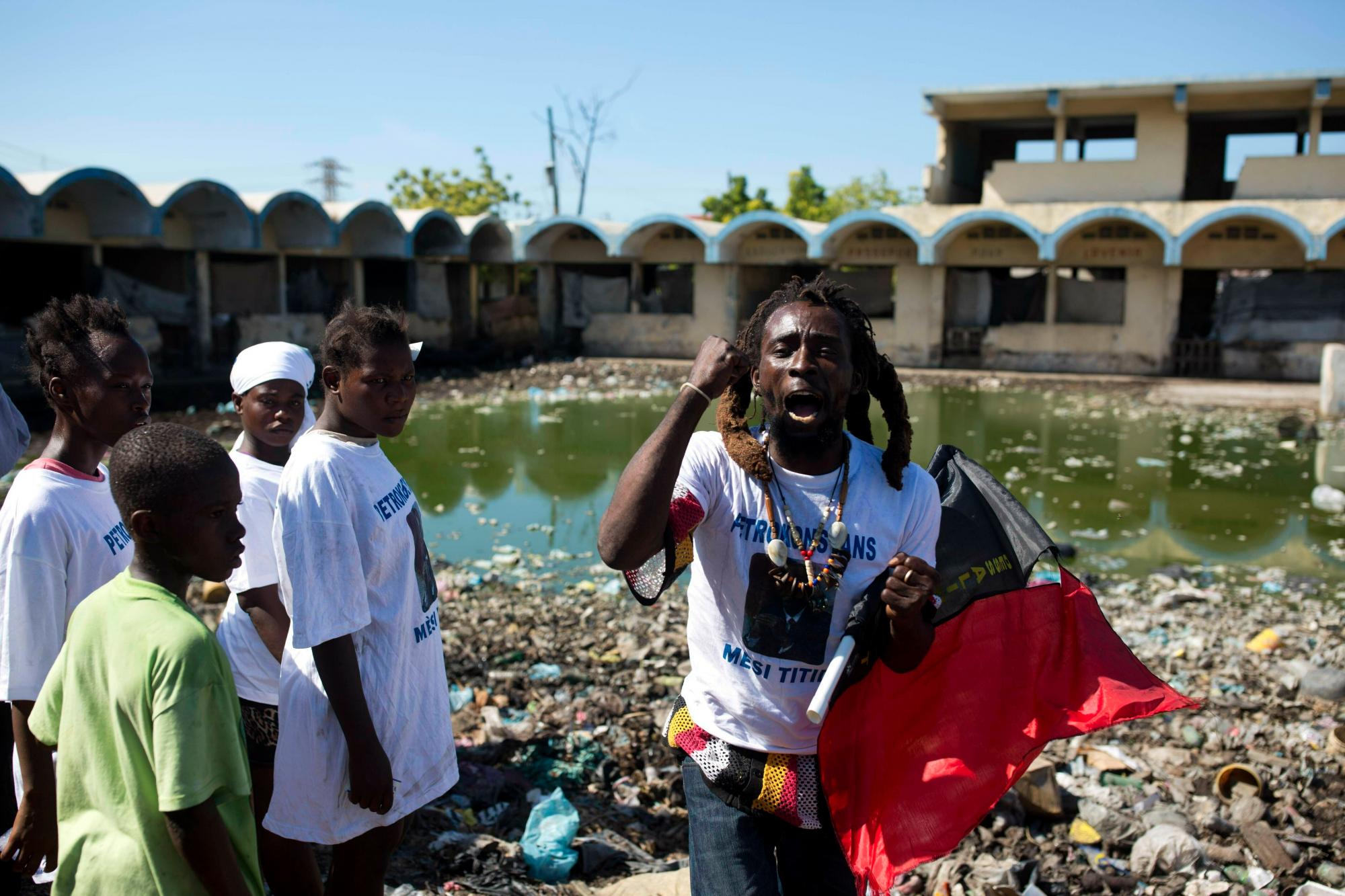 Un hombre que luce una camiseta con una foto del ex presidente Bertrand Aristide denuncia al gobierno mientras la gente se congrega frente a una granja porcina en La Saline, Haití, el 16 de diciembre del 2018.