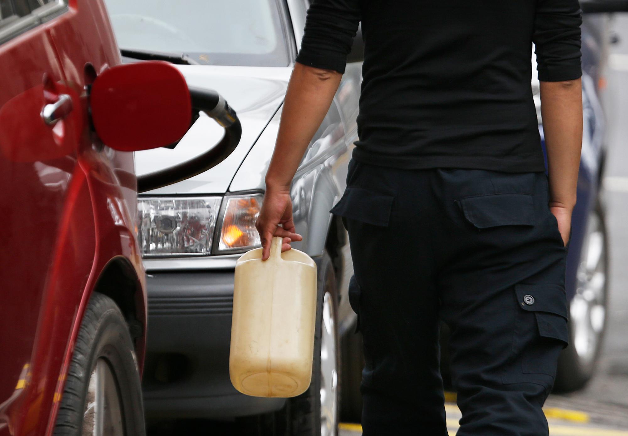 Un hombre lleva un contenedor para llenar con combustible en una estación de servicio, aunque se ha prohibido llenar todo menos un vehículo, durante una escasez en la distribución de combustible en la Ciudad de México.