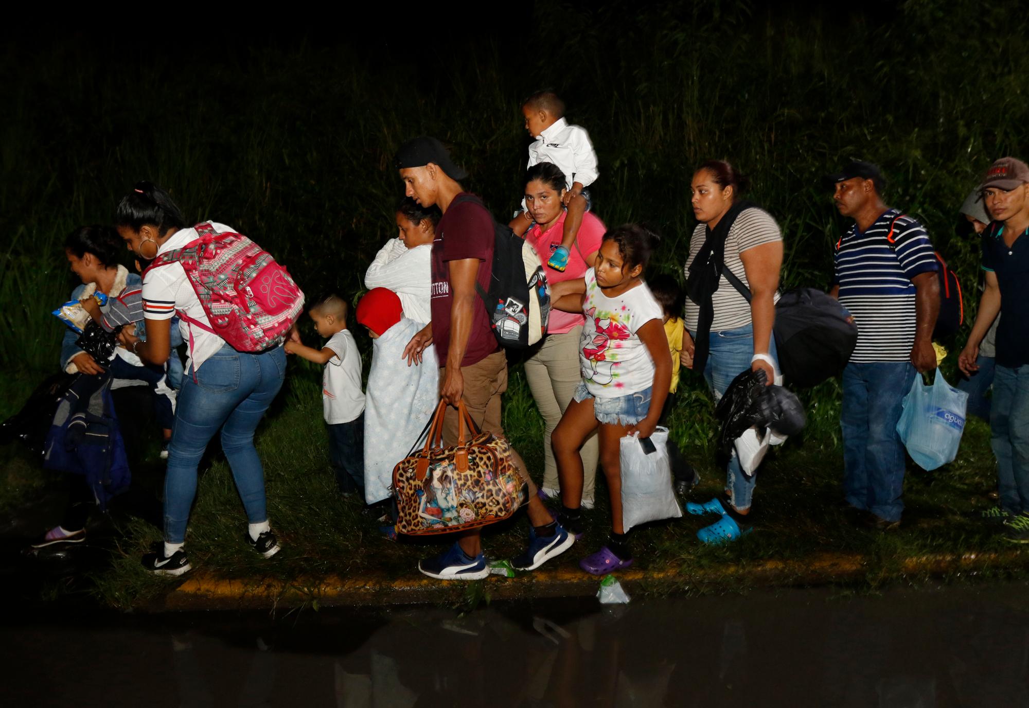 Los migrantes comienzan su viaje bajo una lluvia constante cuando una caravana de varios cientos caminan hacia los Estados Unidos, desde una estación principal de autobuses en San Pedro Sula, Honduras.