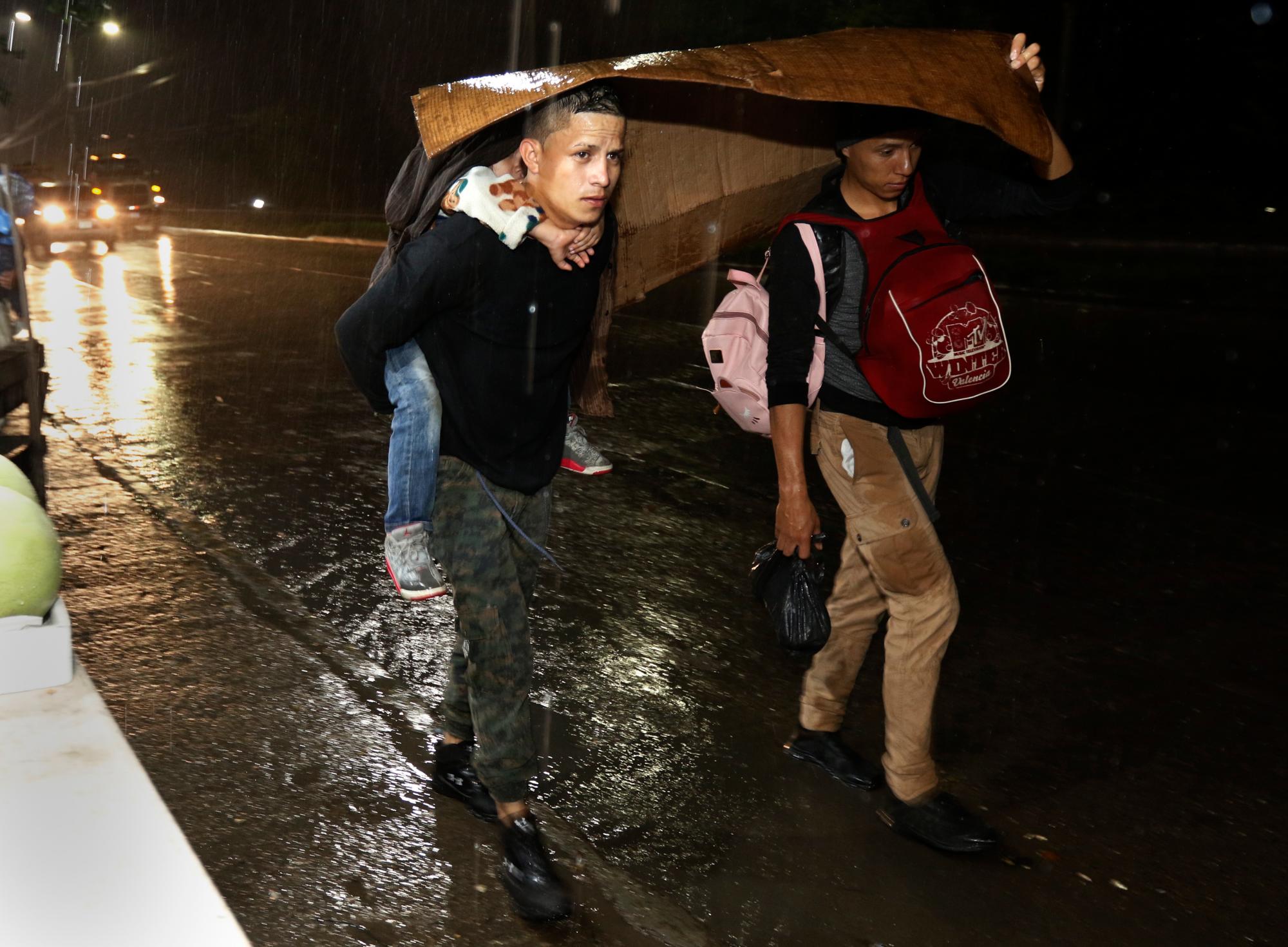 Los migrantes comienzan su viaje hacia los lejanos Estados Unidos,  bajo una lluvia constante mientras una caravana de varios cientos sale a pie desde una estación principal de autobuses en San Pedro Sula, Honduras.