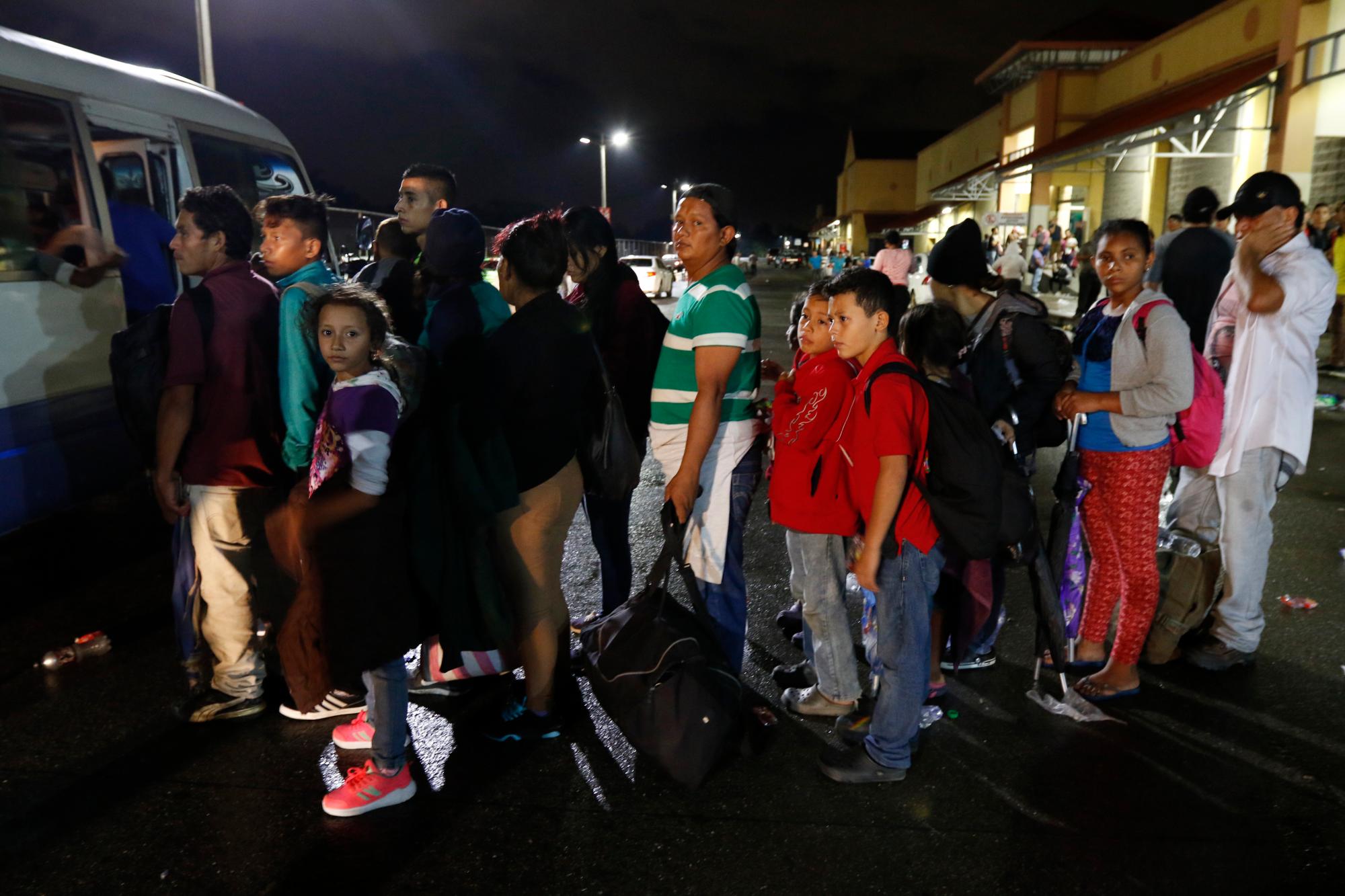 Los migrantes que buscan llegar a los EE. UU. esperan en línea para abordar un autobús hacia la frontera de Honduras con Guatemala, mientras cientos de migrantes parten en autobús ó a pie desde una estación principal de autobuses en San Pedro Sula, Honduras.