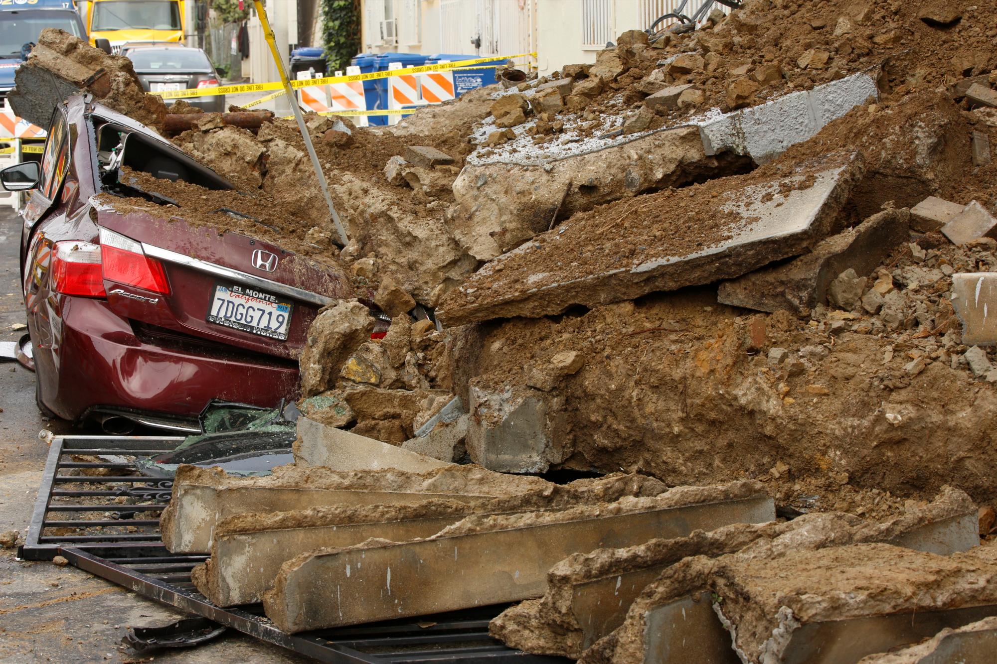 Un vehículo está enterrado bajo losas de barro y cemento cuando los escombros se deslizaron temprano en la mañana desde debajo de una casa en Los Ángeles, el viernes 18 de enero de 2019. Nadie resultó herido. La lluvia de tres días hizo mella en la sequía de California.