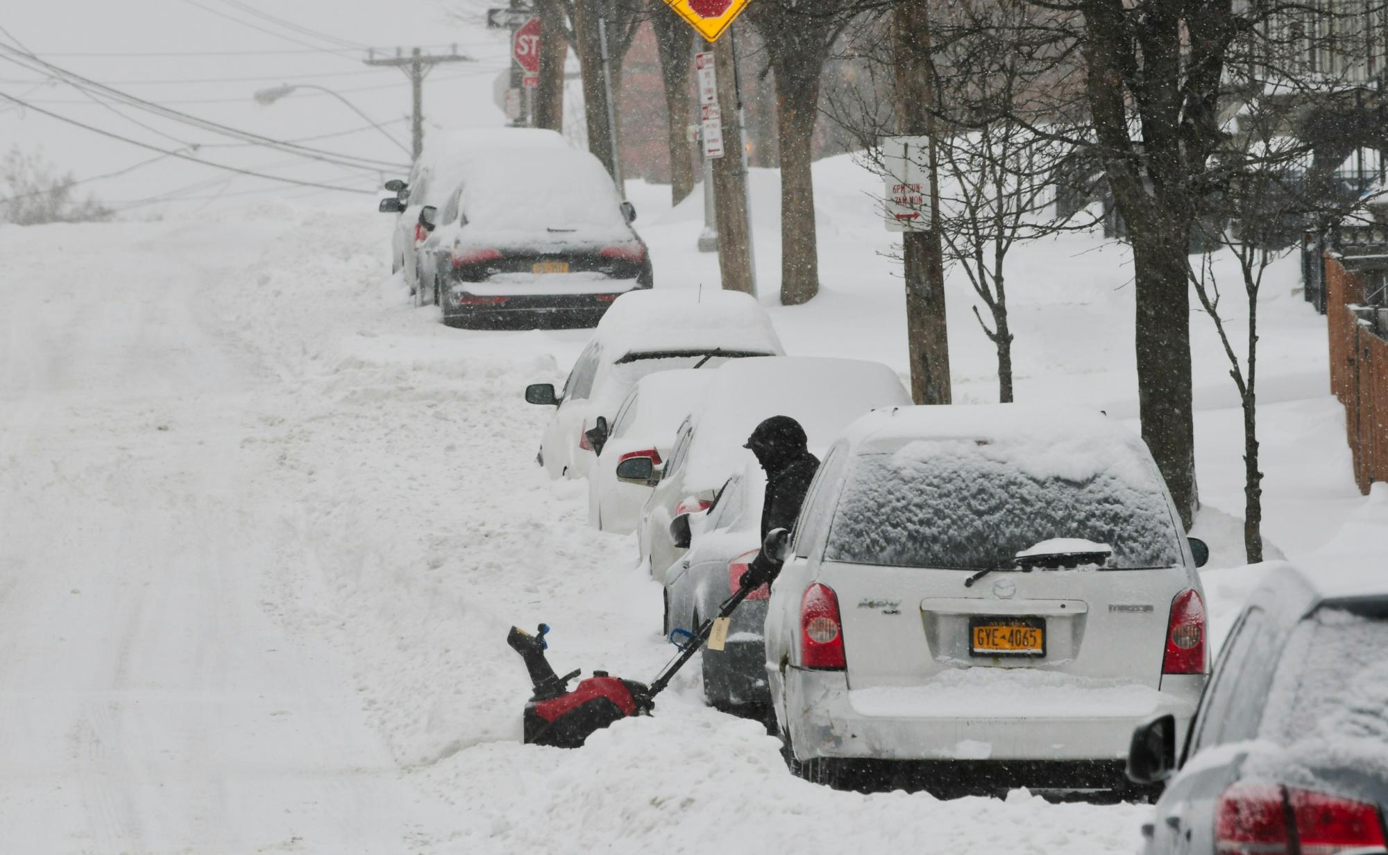 Un hombre usa un quitanieves para limpiar la nieve alrededor de los autos el domingo 20 de enero de 2019, en Albany, Nueva York.