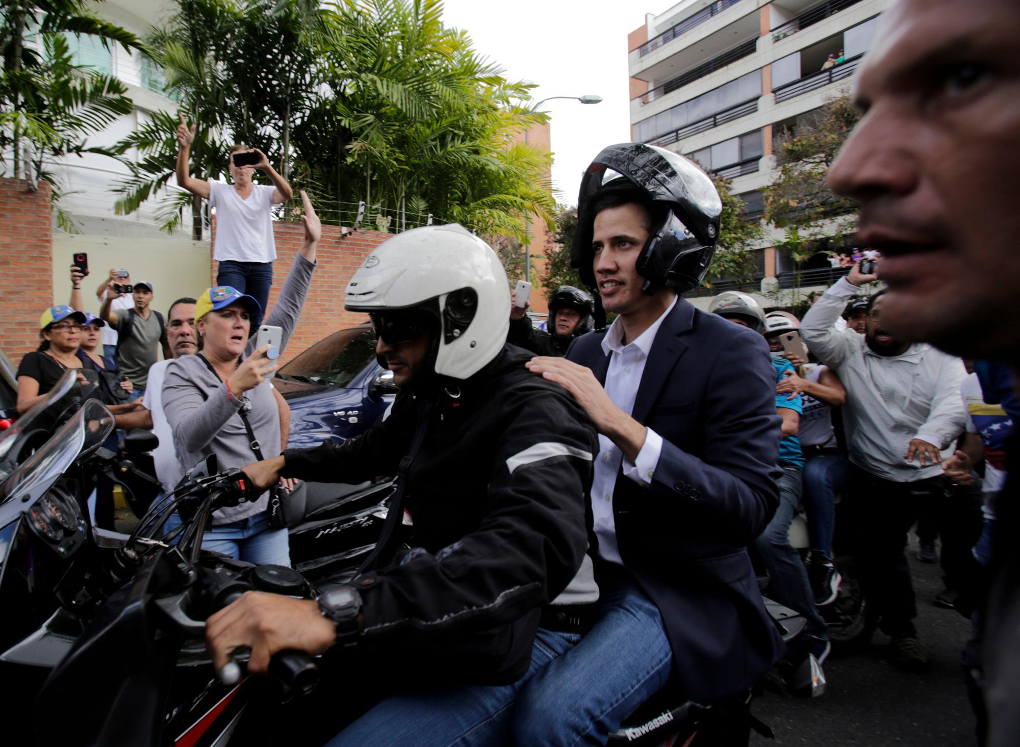 Juan Guaido, jefe del congreso de oposición dirigido por Venezuela, monta en la parte trasera de una motocicleta mientras saluda a sus partidarios luego de declararse presidente interino del país sudamericano en un mitin exigiendo la renuncia del presidente Nicolás Maduro, en Caracas, Venezuela, el miércoles 23 de enero de 2019.
