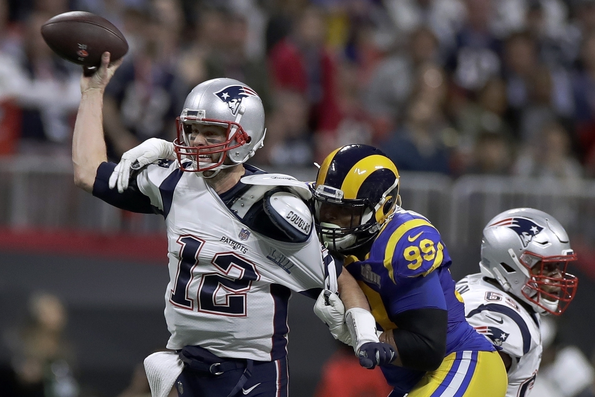 Tom Brady (12) de los Patriots de Nueva Inglaterra trata de pasar el balón ante el asedio de Aaron Donald (99) de los Rams de Los Ángeles durante la primera mitad del Super Bowl, el domingo 3 de febrero de 2019, en Atlanta.