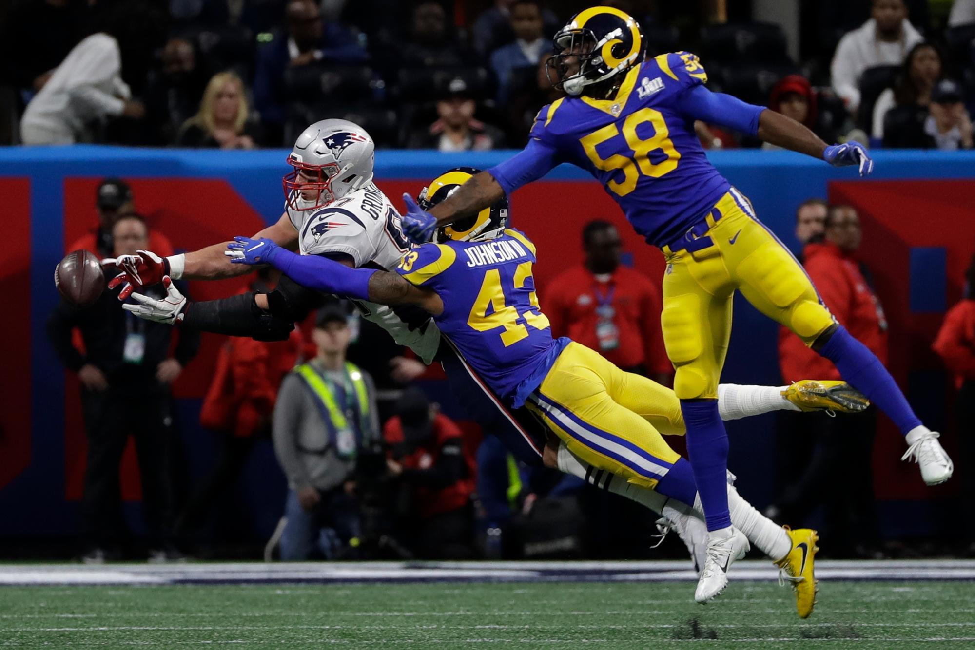 Rob Gronkowski (87) de los Patriots se estira para atrapar un pase mientras Cory Littleton (58) Rams de Los Angeles  y John Johnson III (43) defienden, durante la primera mitad del partido de fútbol Super Bowl 53 de la NFL el domingo 3 de febrero. , 2019, en Atlanta.