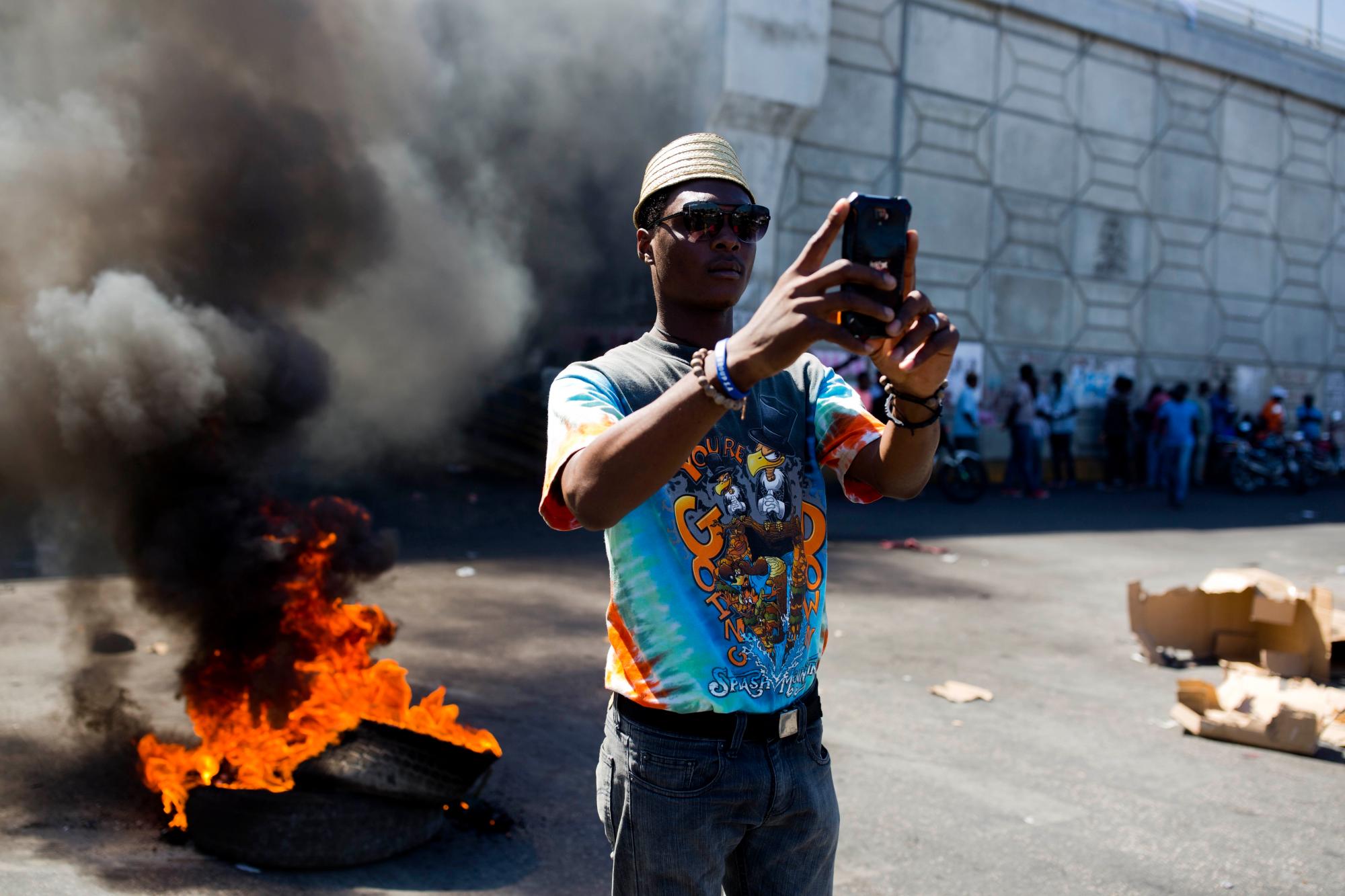 Un manifestante se toma un selfie frente a una barricada en llamas durante una protesta que exige la renuncia del presidente Jovenel Moïse en Puerto Príncipe, Haití.