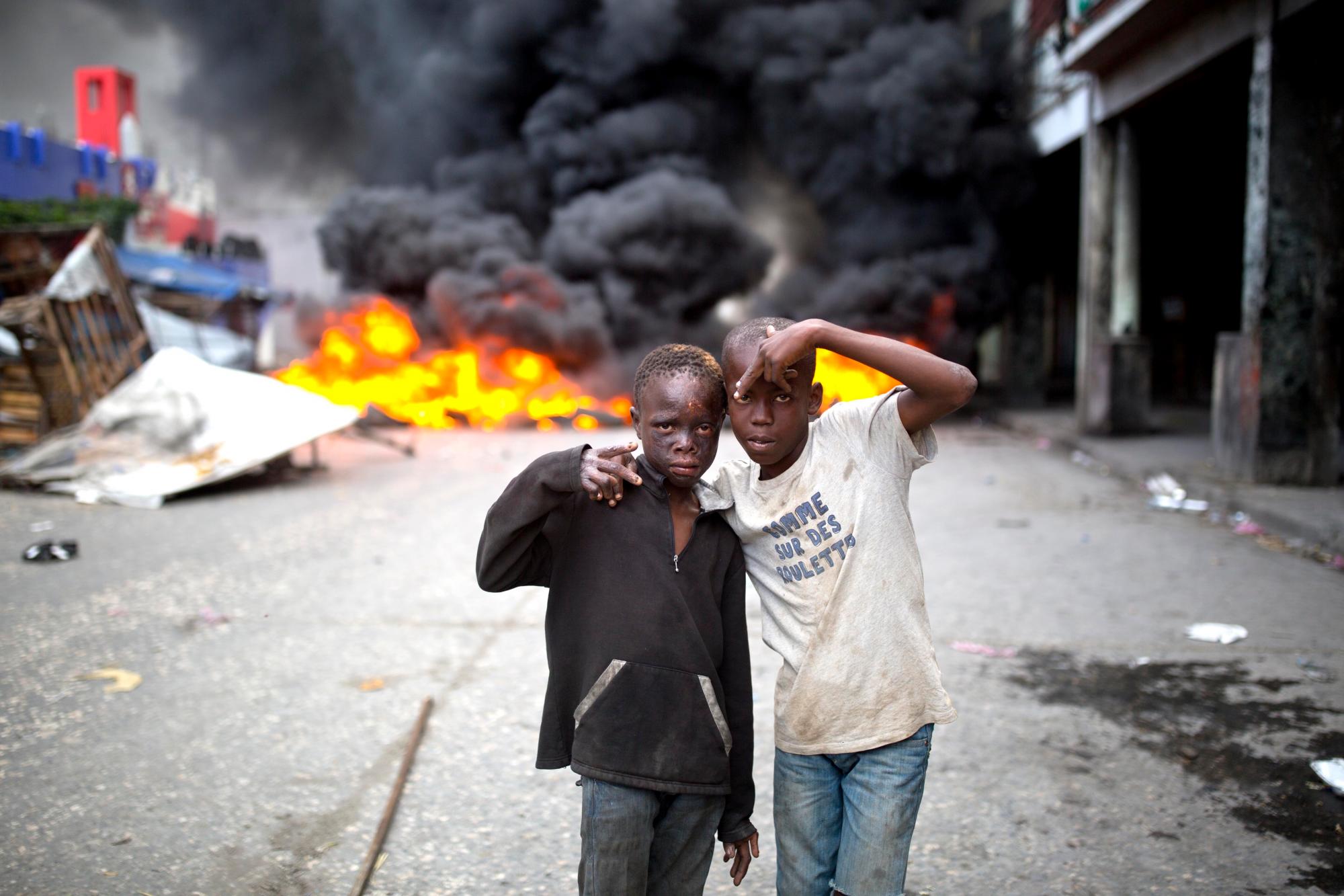 Los jóvenes sin hogar se colocan frente a un bloque de carreteras incendiado por manifestantes que exigen la renuncia del presidente Jovenel Moïse en Puerto Príncipe, Haití.
