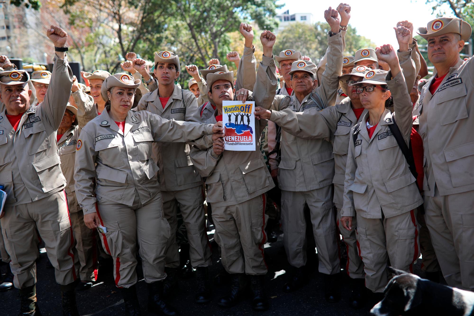Miembros de la Milicia Bolivariana sostienen un póster durante una manifestación oficialista en Caracas, Venezuela, el martes 12 de febrero de 2019. Casi tres semanas después de que la administración de Trump respaldó un esfuerzo total para expulsar al presidente venezolano Nicolás Maduro, el asediado El líder socialista mantiene fuertes y desafía las predicciones de una desaparición inminente.