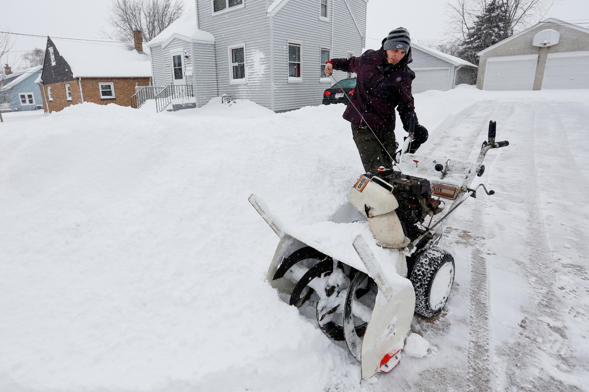 Charlie Zurek inicia su quitanieves para despejar la entrada de su vecino mientras la nieve cubre el área, el martes 12 de febrero de 2019, en Manitowoc, Wisconsin