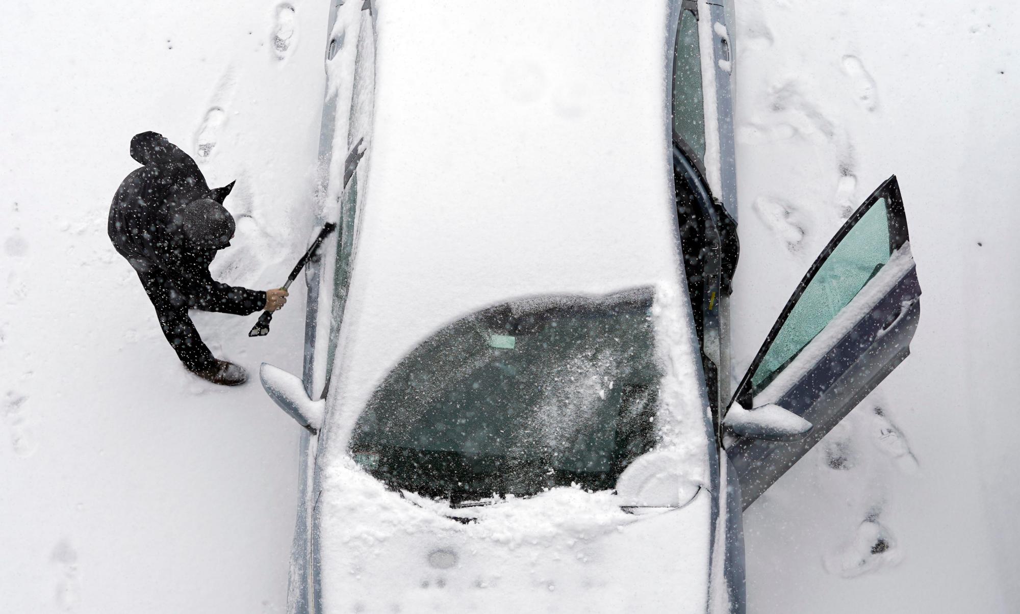 Un hombre limpia su automóvil en McKay Street mientras cae nieve en Pittsfield, Mass., Martes, 12 de febrero de 2019.
