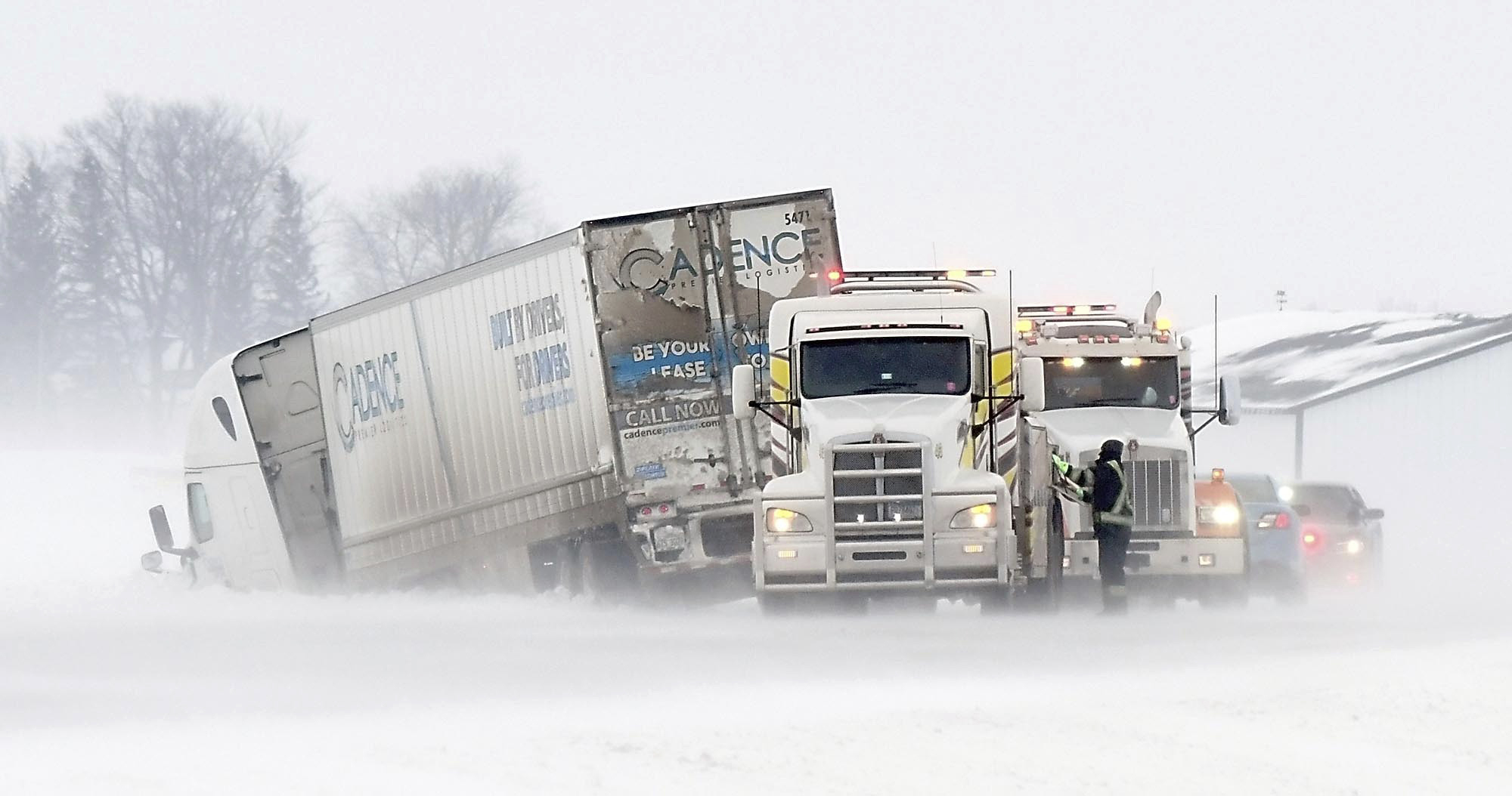 Los conductores de camiones de remolque trabajan para sacar un semirremolque de una zanja en la nieve a lo largo de la Carretera 60 al sur de Madison Lake, Minnesota, el martes 12 de febrero de 2019.